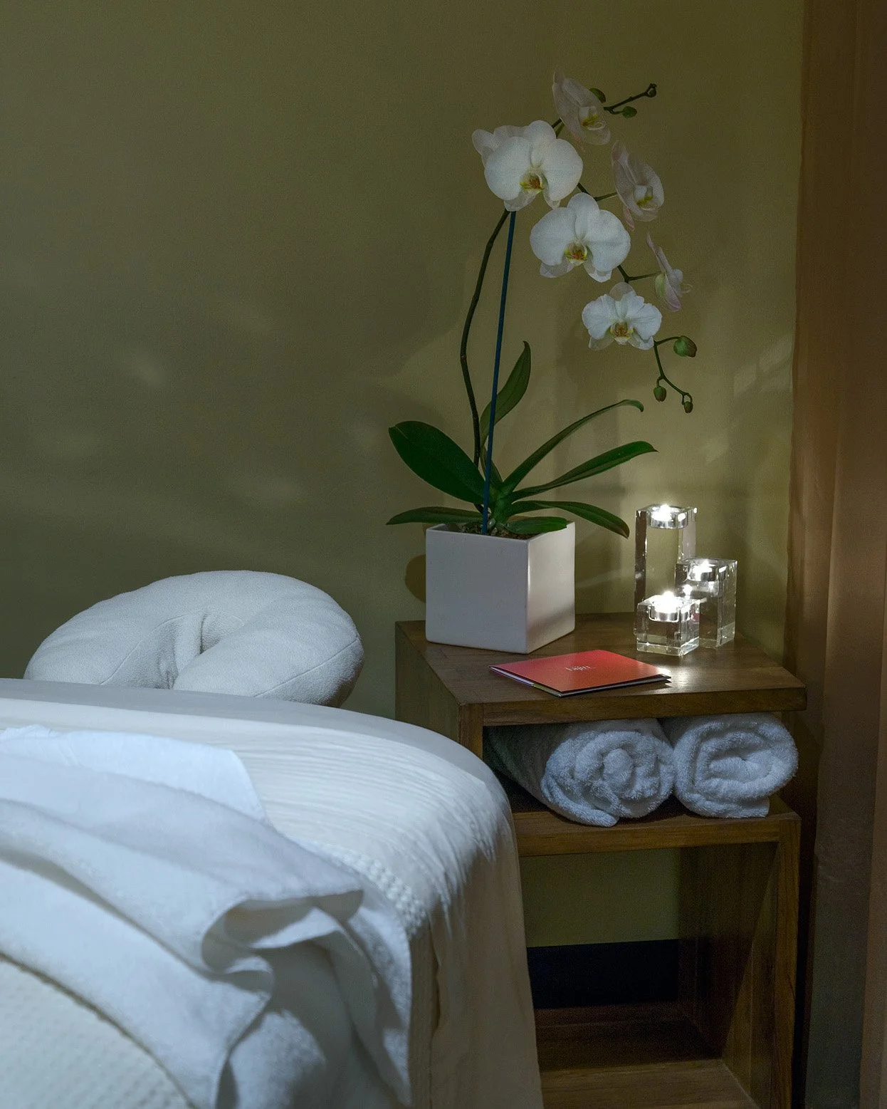 A quiet and candle lit spa treatment room with heated tables and plush linens, designed for the ultimate in relaxation at bijin salon & spa in Kansas City.
