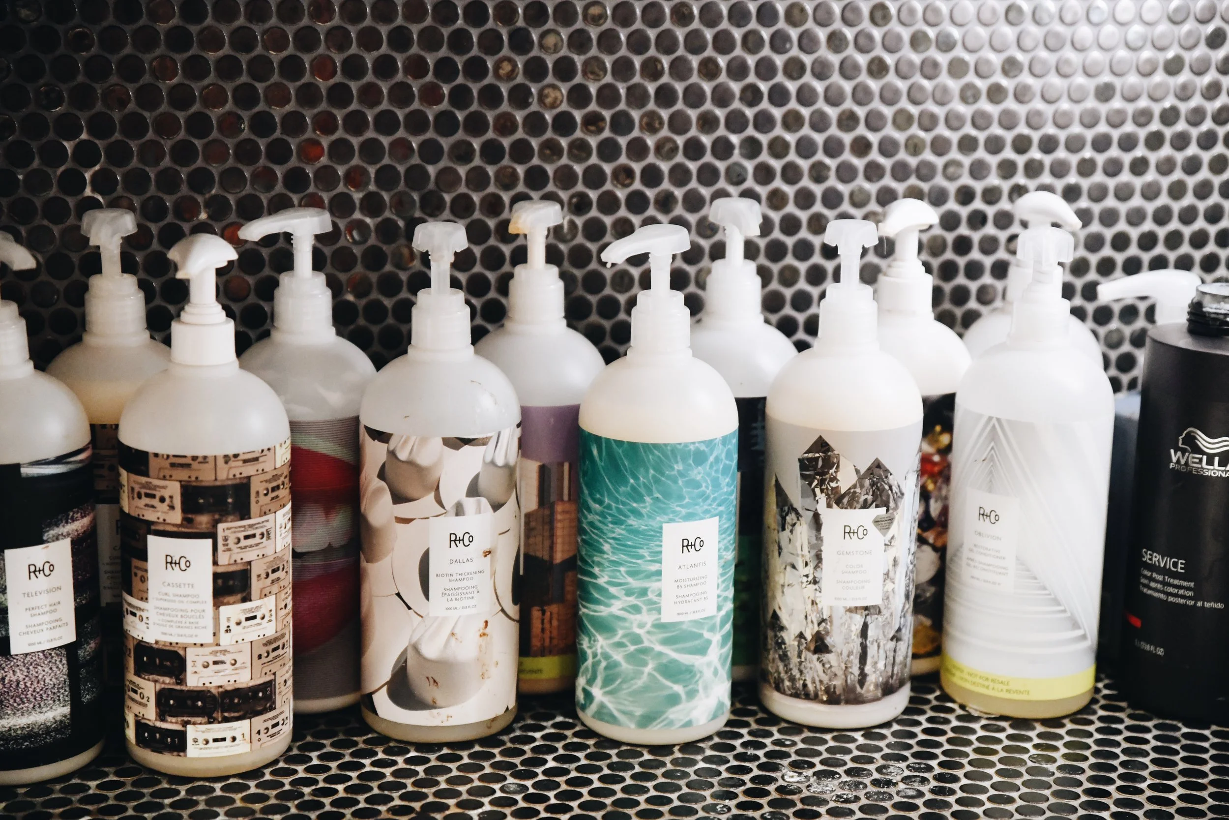 A full range of R+Co shampoos ready for use in the studio at bijin salon & spa in Prairie Village.
