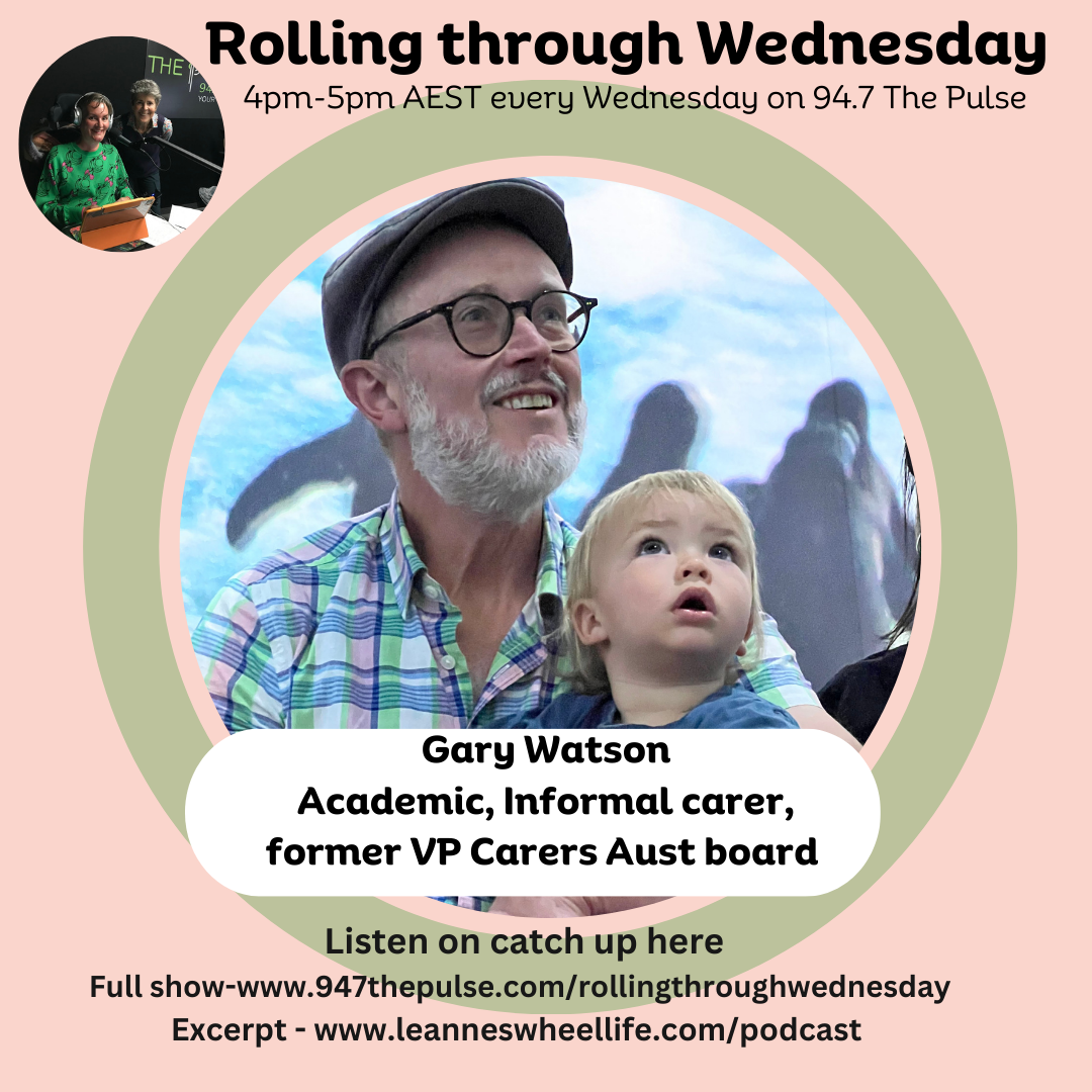 Smiling man with a white beard flat cap and dark room glasses holding a small toddler on his lap they are both mesmerised by the video around them