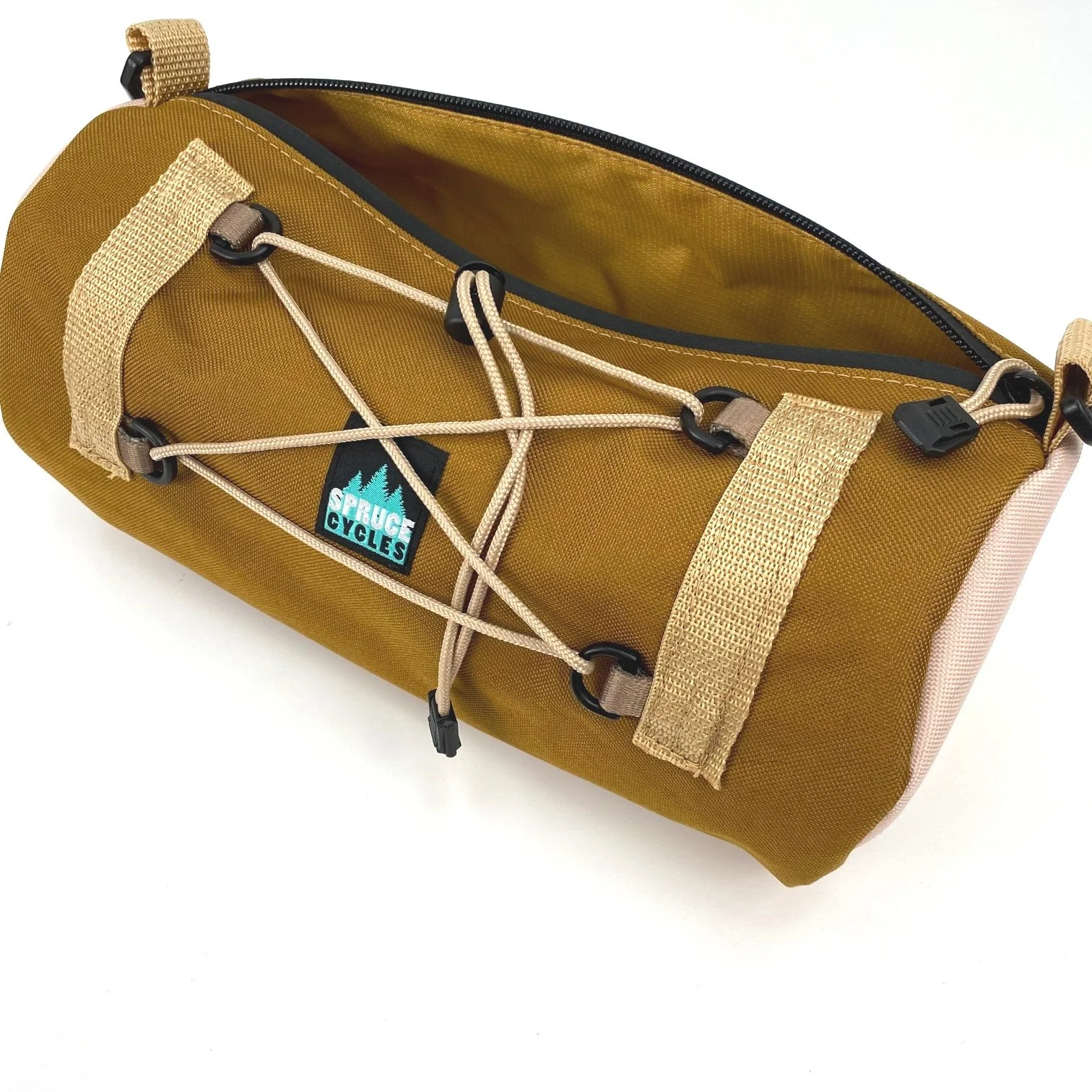 A brown dry bag with beige straps and a front bungee cord with black clips, open at the top, with a partially visible yellow interior and a brand label 'Spruce Cycles' on the front.