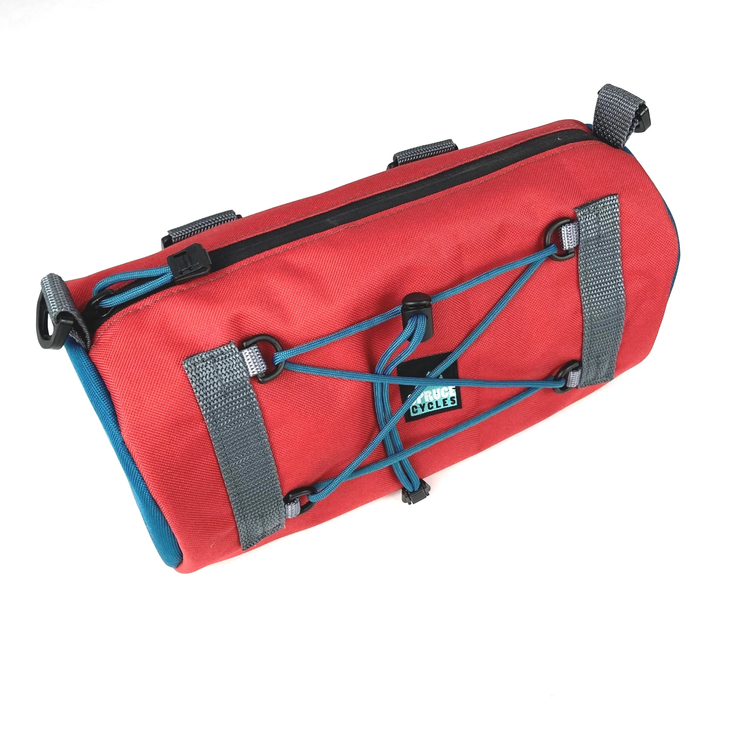 Red bike handlebar bag with black zipper, gray straps, blue bungee cords, and a 'FUGUE CYCLES' logo patch on the front.