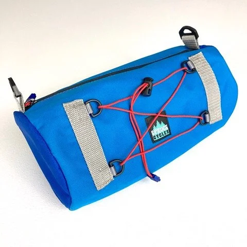 A blue and gray cycling bag with red elastic cords and a small label that says 'CYCLING CYCLES'.