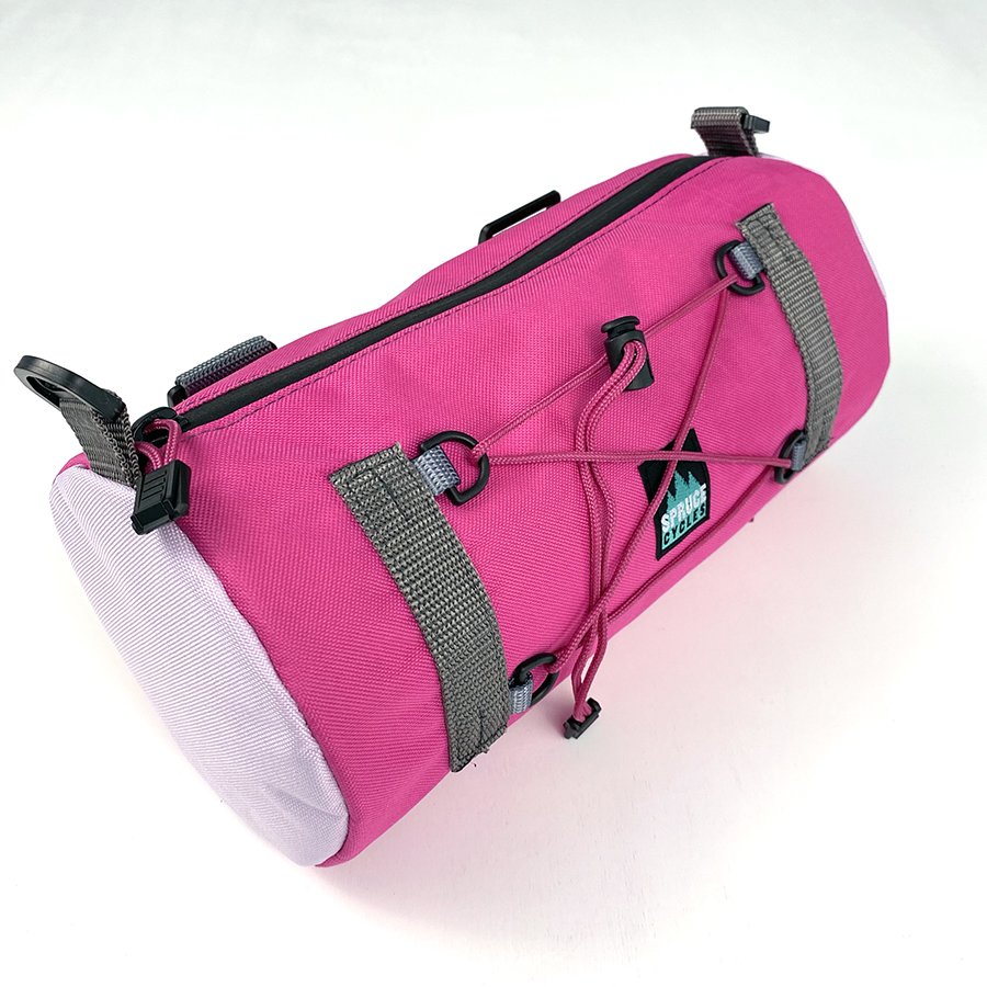A pink Spruce Cycles bicycle frame bag with black zipper, gray straps, and external bungee cords against a white background.