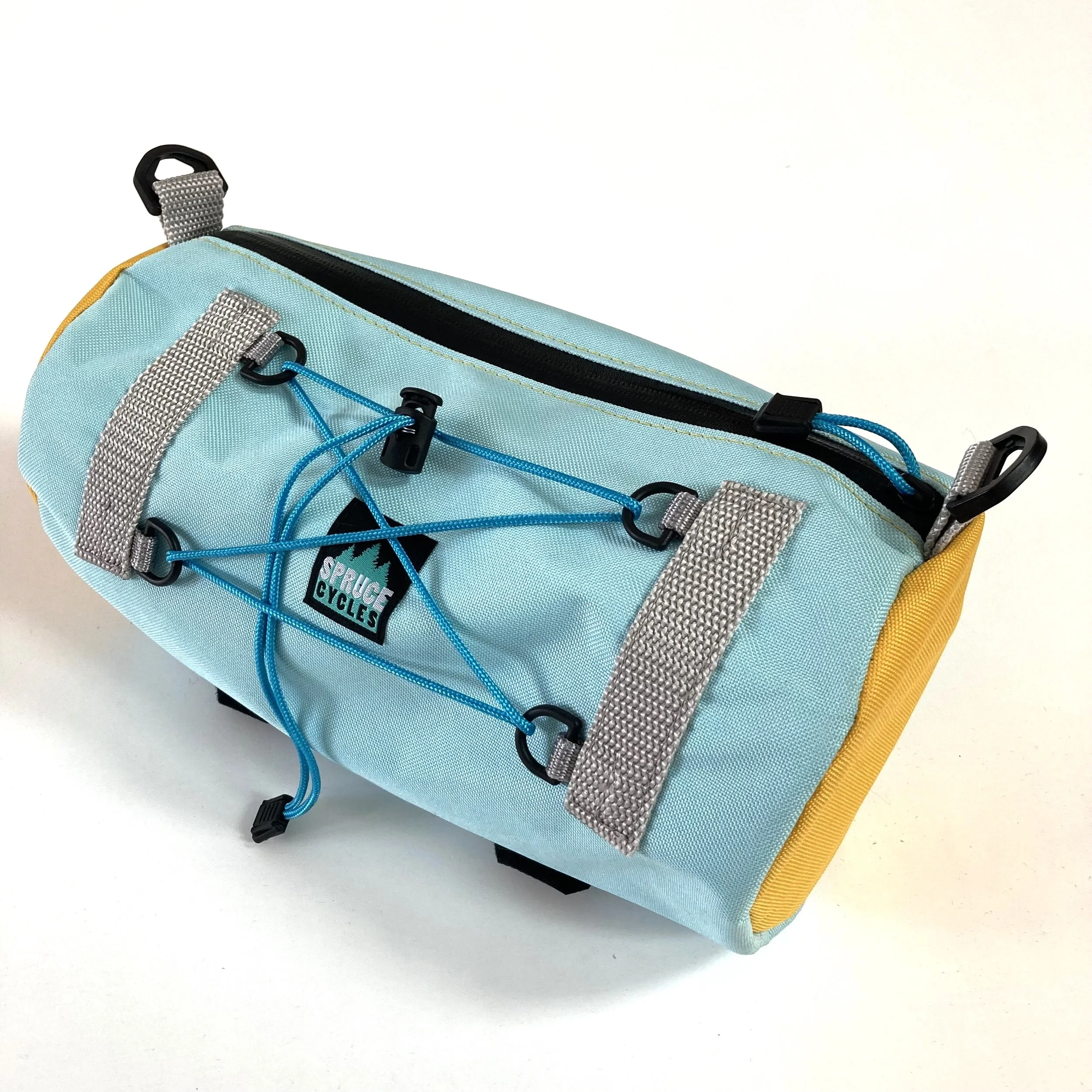 A light blue and yellow bike handlebar bag with gray straps, a black zipper, and a blue bungee cord with hooks.