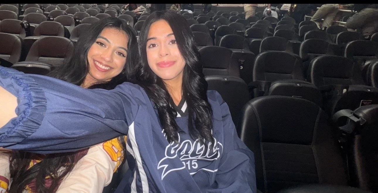 Two women taking a selfie in an empty sports stadium with many black seats.