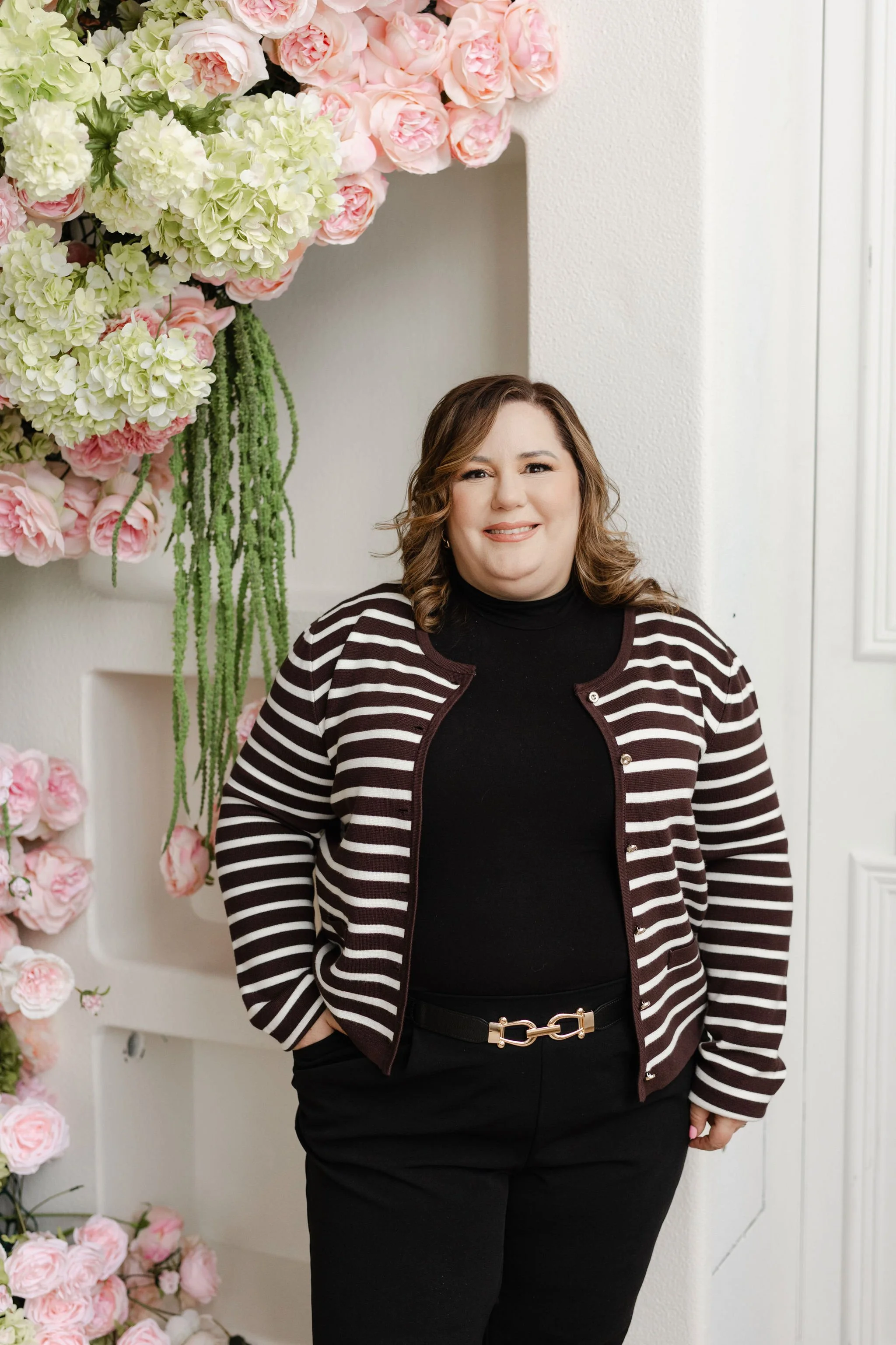 Claudia is setting a table with a floral centerpiece and elegant tableware.