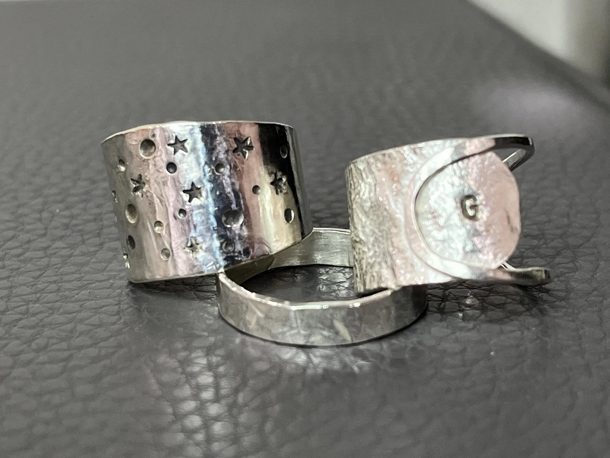 3 silver rings on a grey background