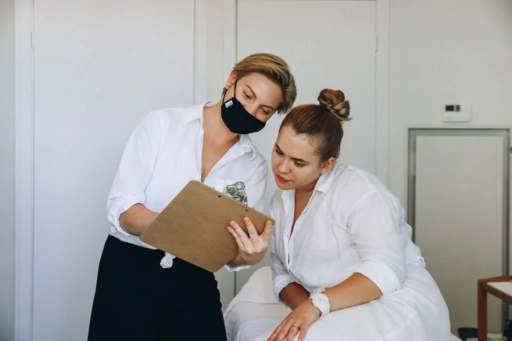 Massage therapist and her patient in an initial consultation and assesment. Both are female and wearing white