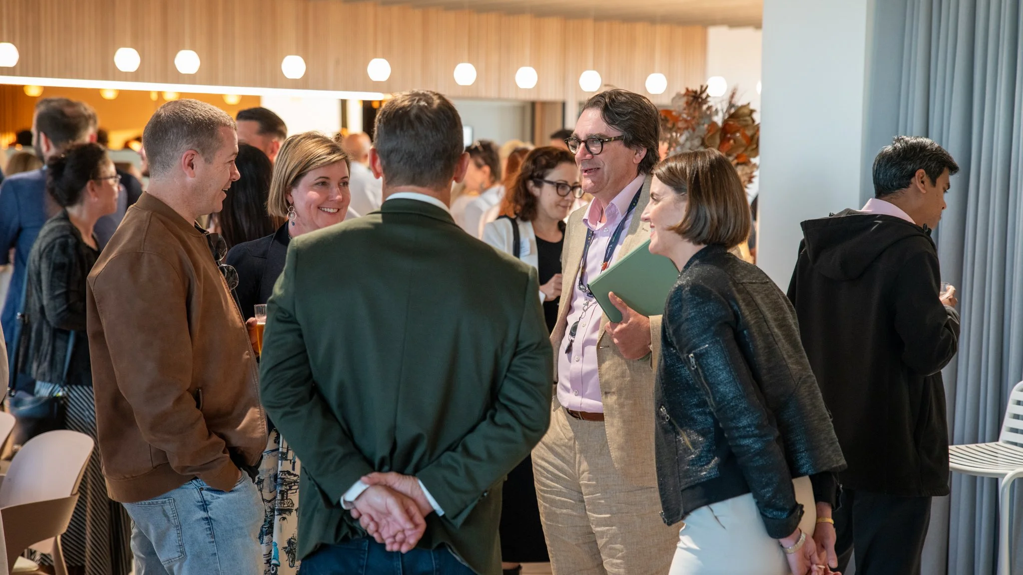 Group of professionals engaged in conversation at a networking event or conference in a modern indoor space.