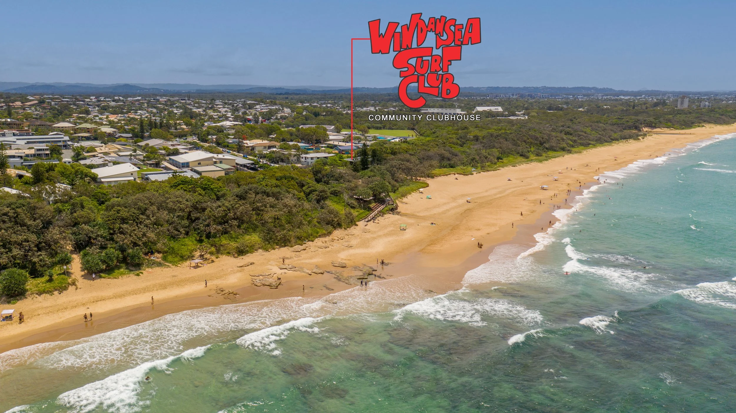 Aerial view of a beach with people walking along the shore, waves crashing onto the sand, greenery behind the beach, and a residential area further inland. A red graphic says 'Wind and Sea Surf Club Community Clubhouse' over the scene.