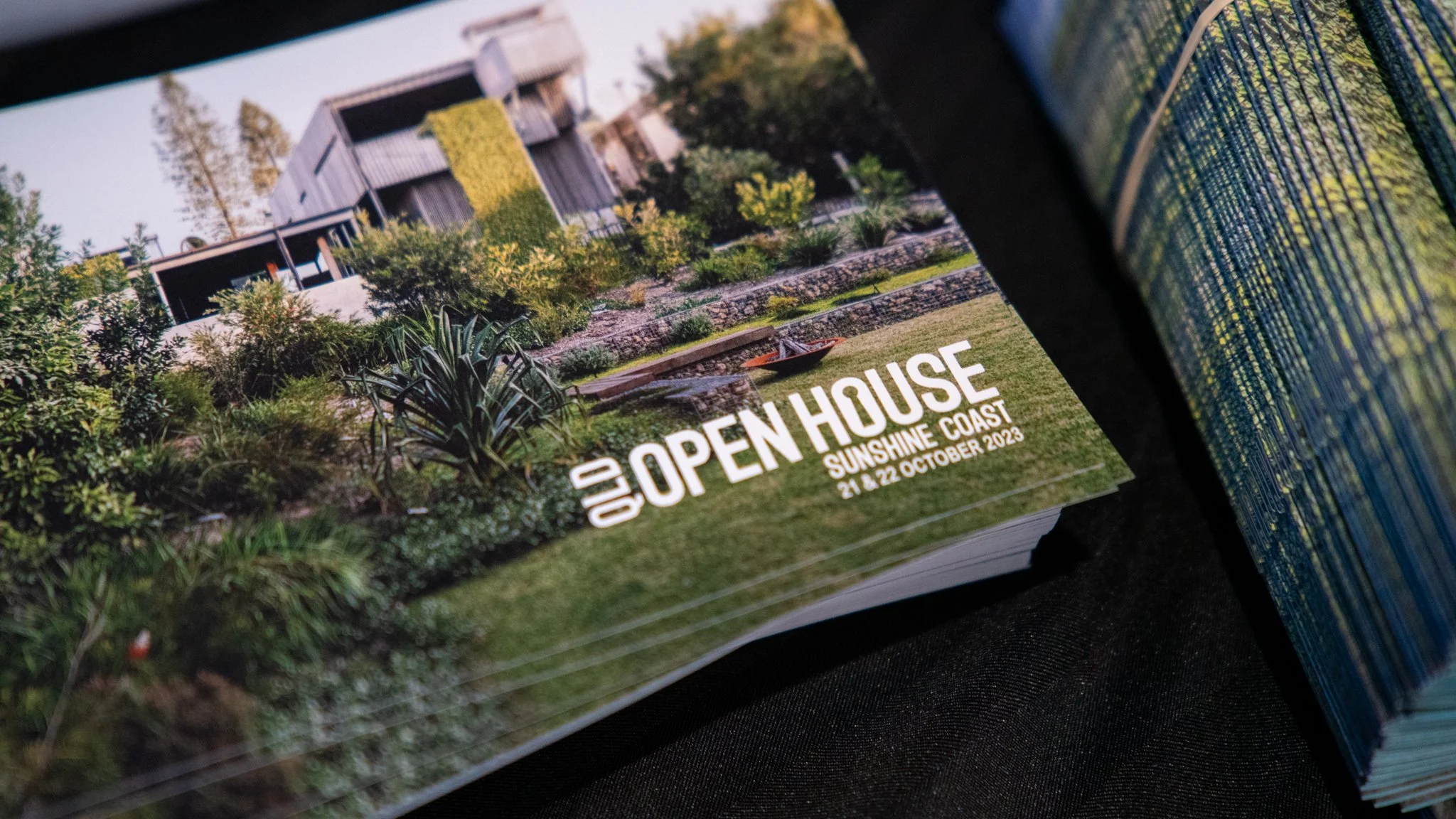 Promotional flyer for an open house event on October 21-22, 2023, in Sunshine Coast, featuring a modern house with landscaped garden, greenery, and outdoor seating.