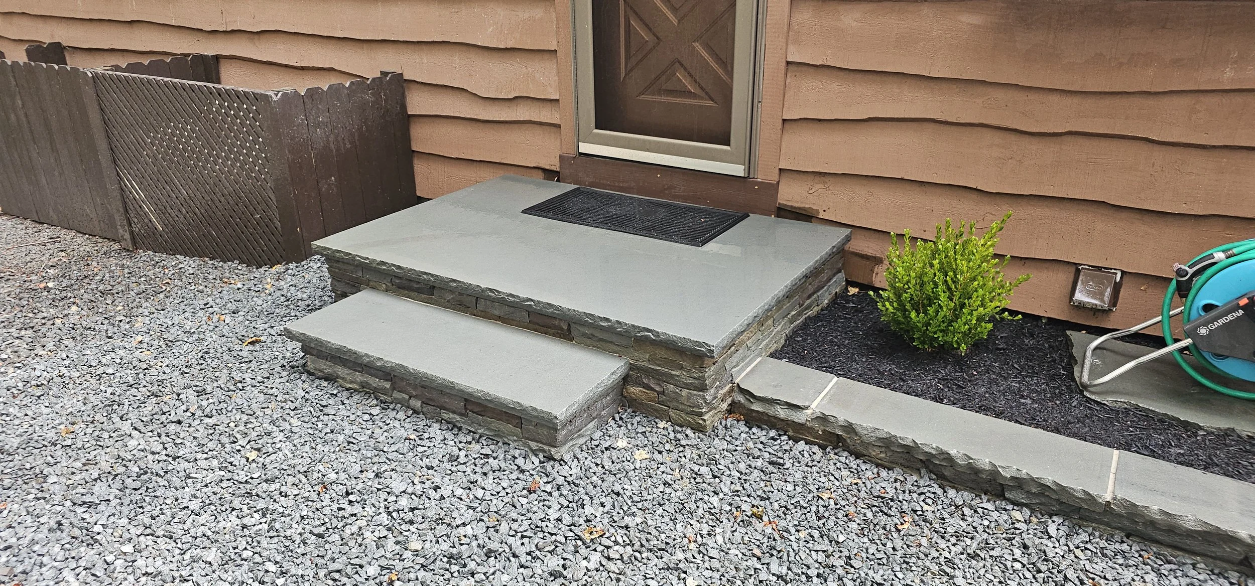 Reinforced concrete landing, with stacked stone veneer, and solid bluestone tread