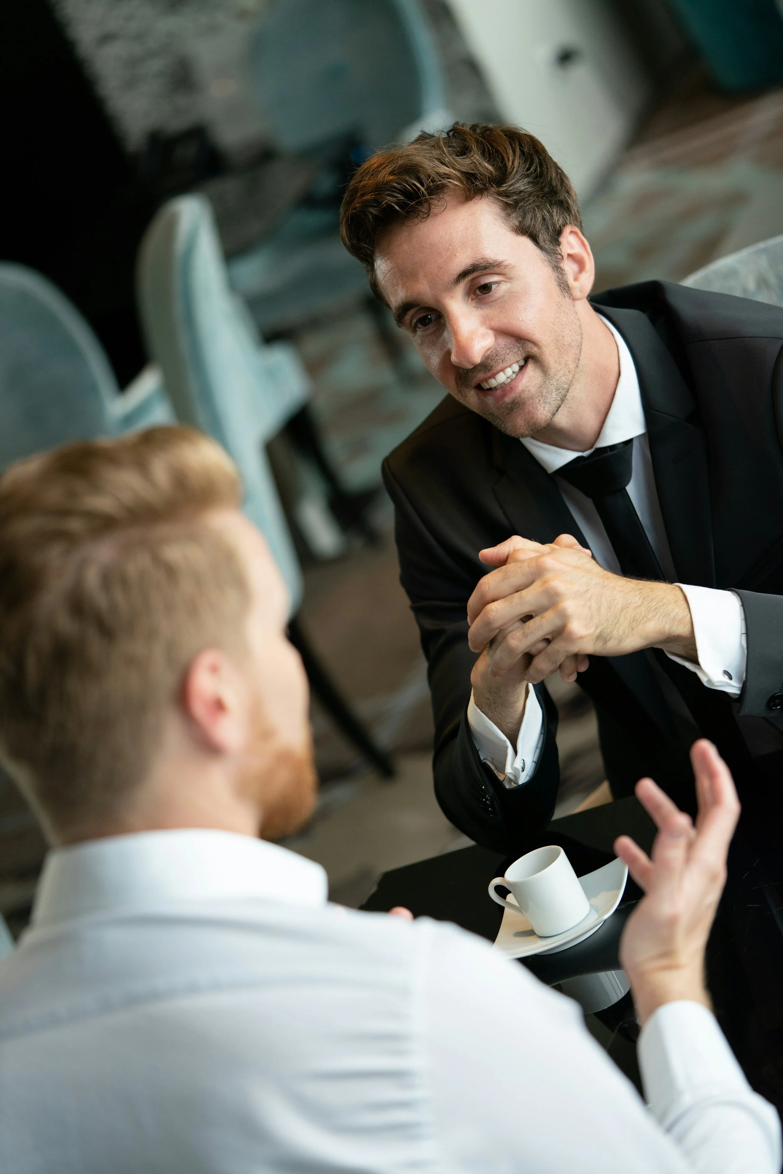 Two male leaders chatting over coffee one facing camera and one away