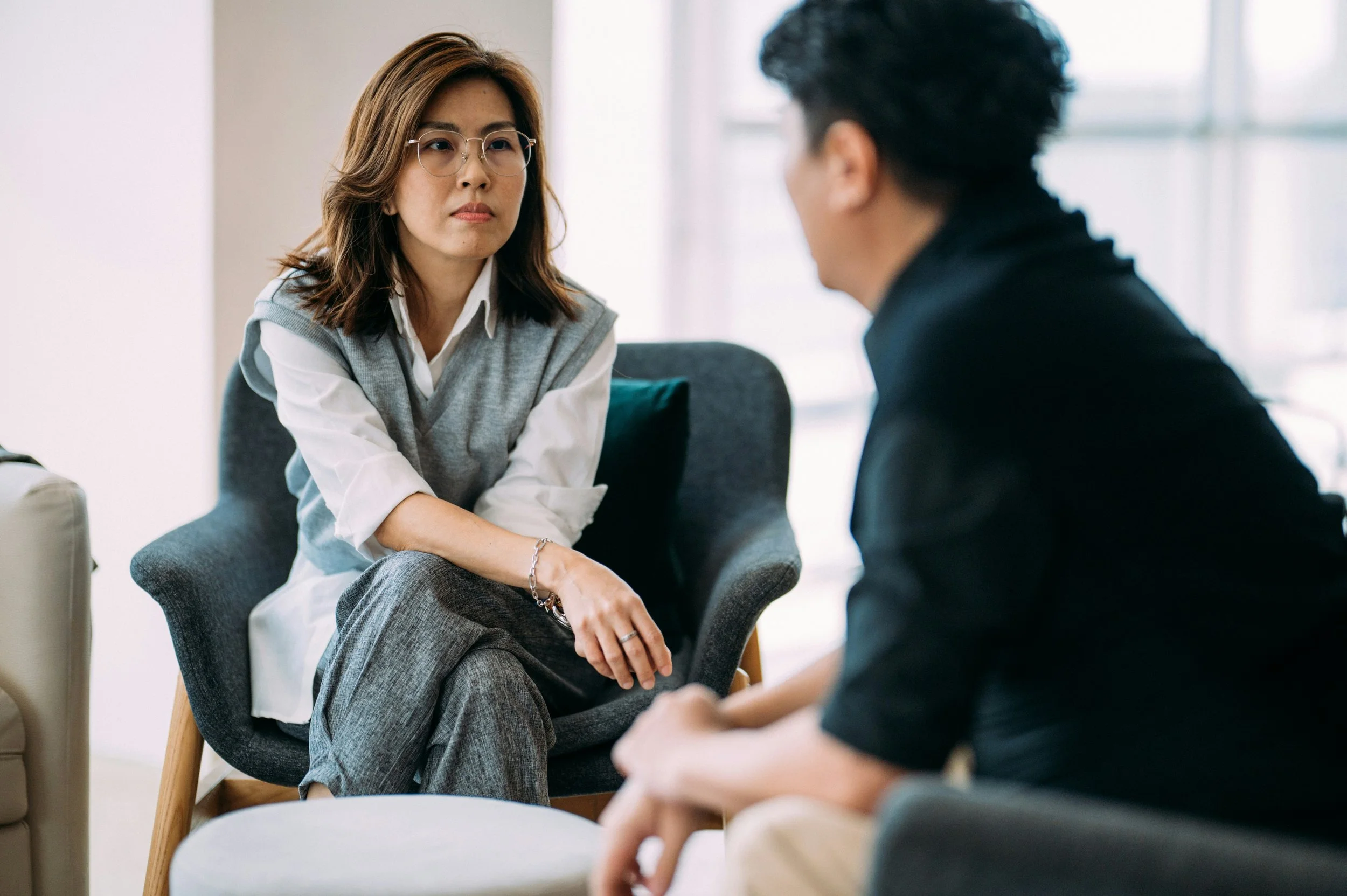Asian business woman in glasses having serious talk with male worker in black top