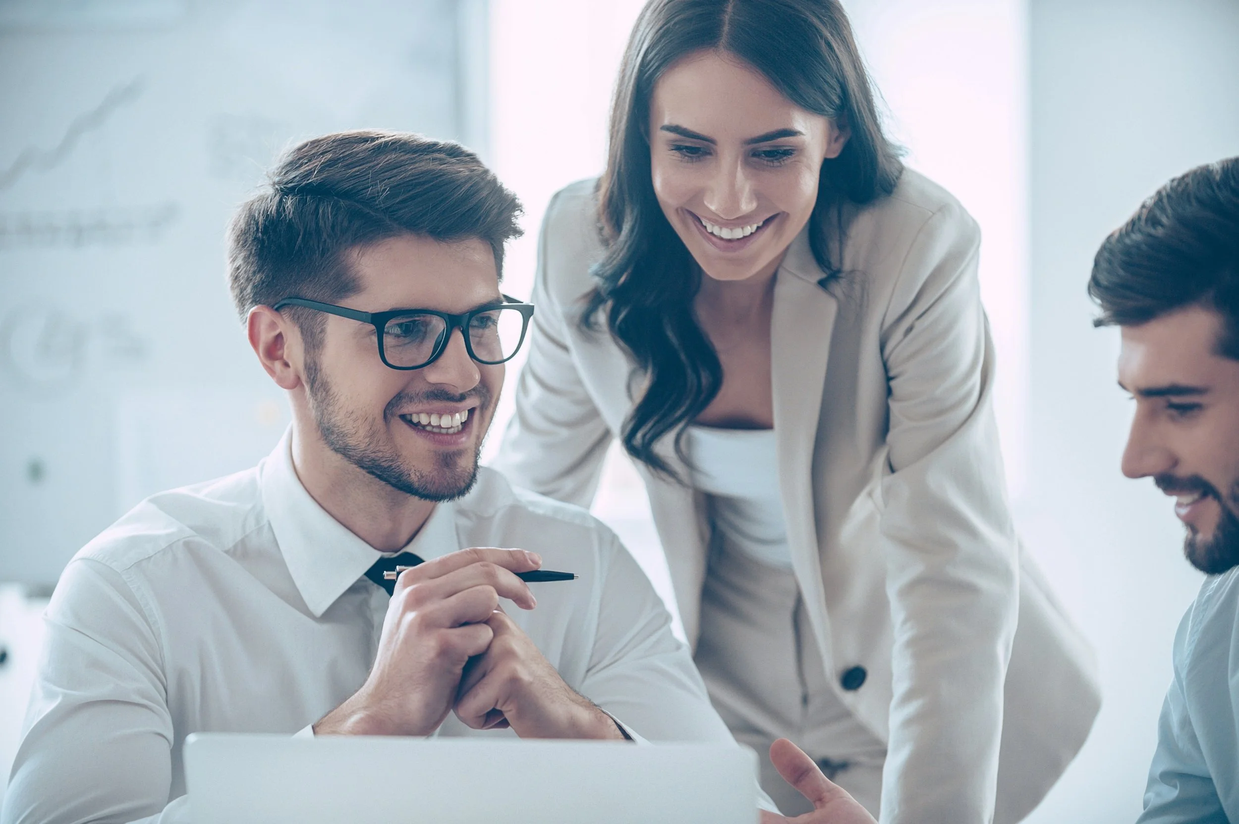 Colleagues collaborating closely around a laptop, reflecting openness, trust, and authentic leadership in practice.