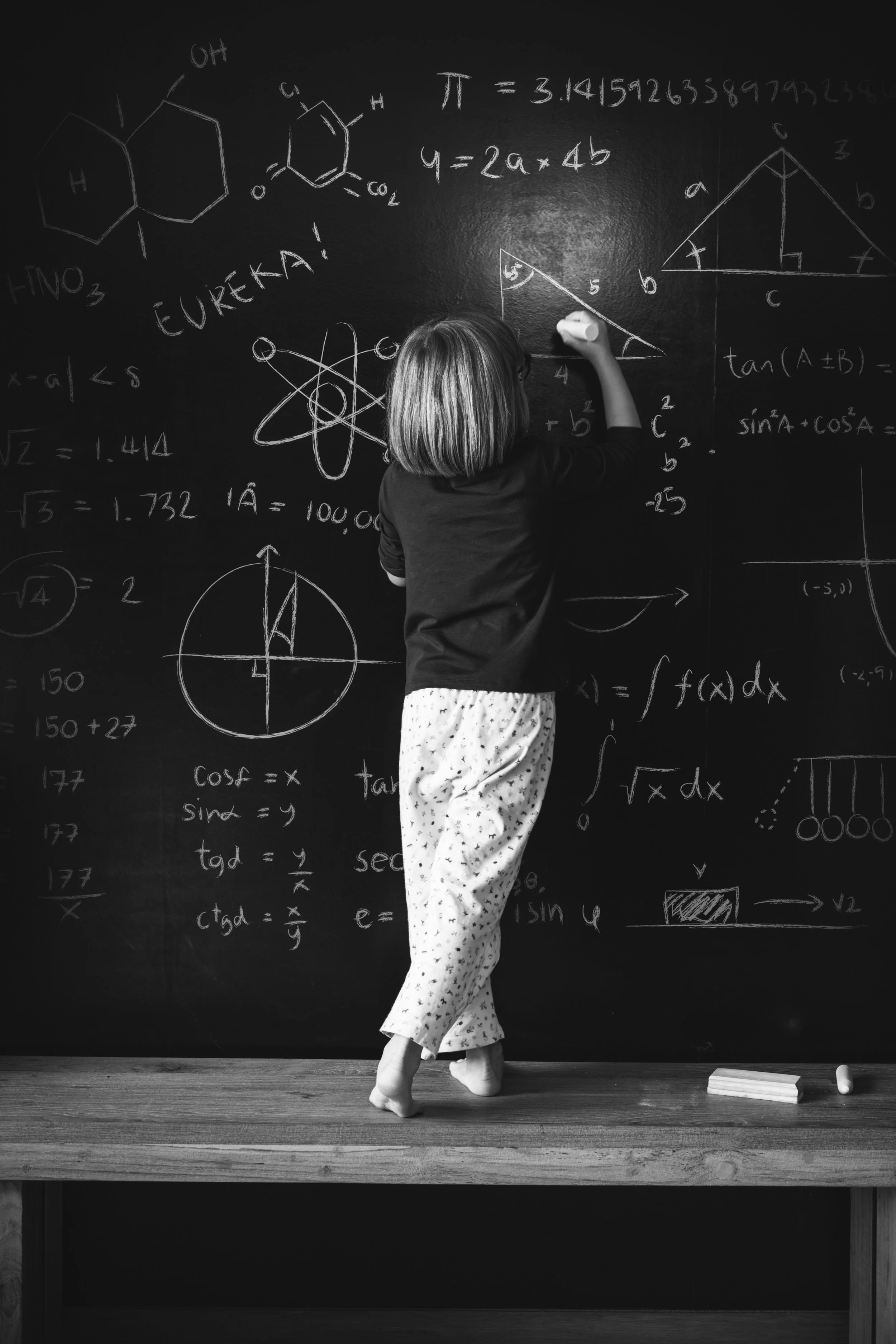 Black and white photo of woman writing on a blackboard with maths calculations