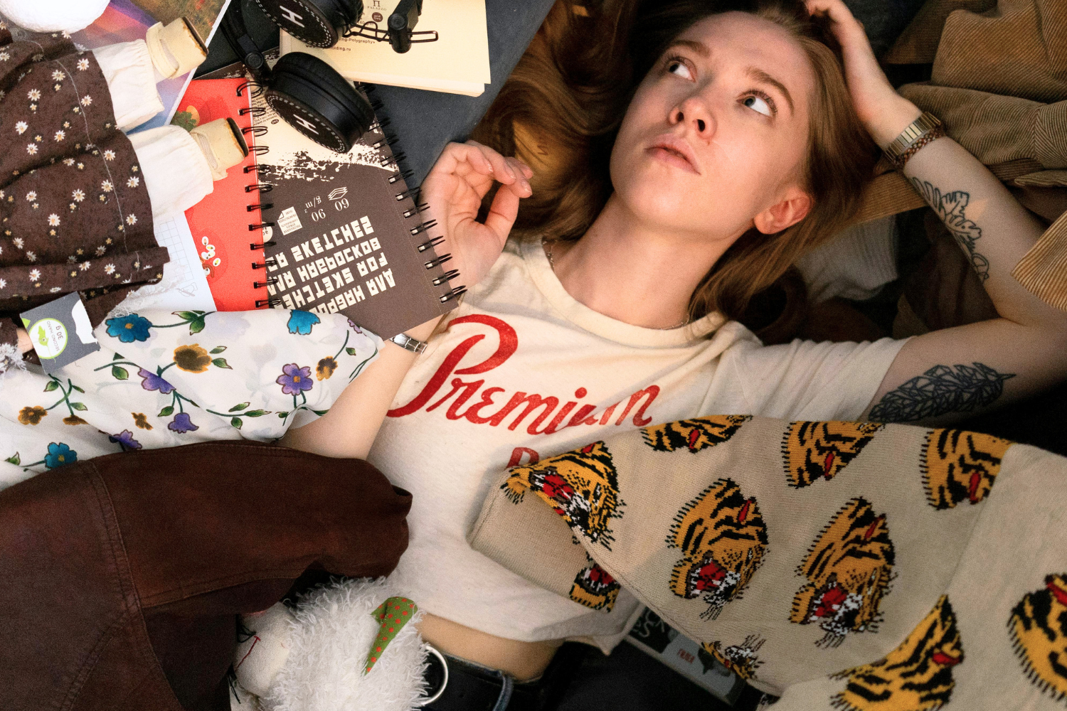 Woman lying on the floor surrounded by clothes and belongings.