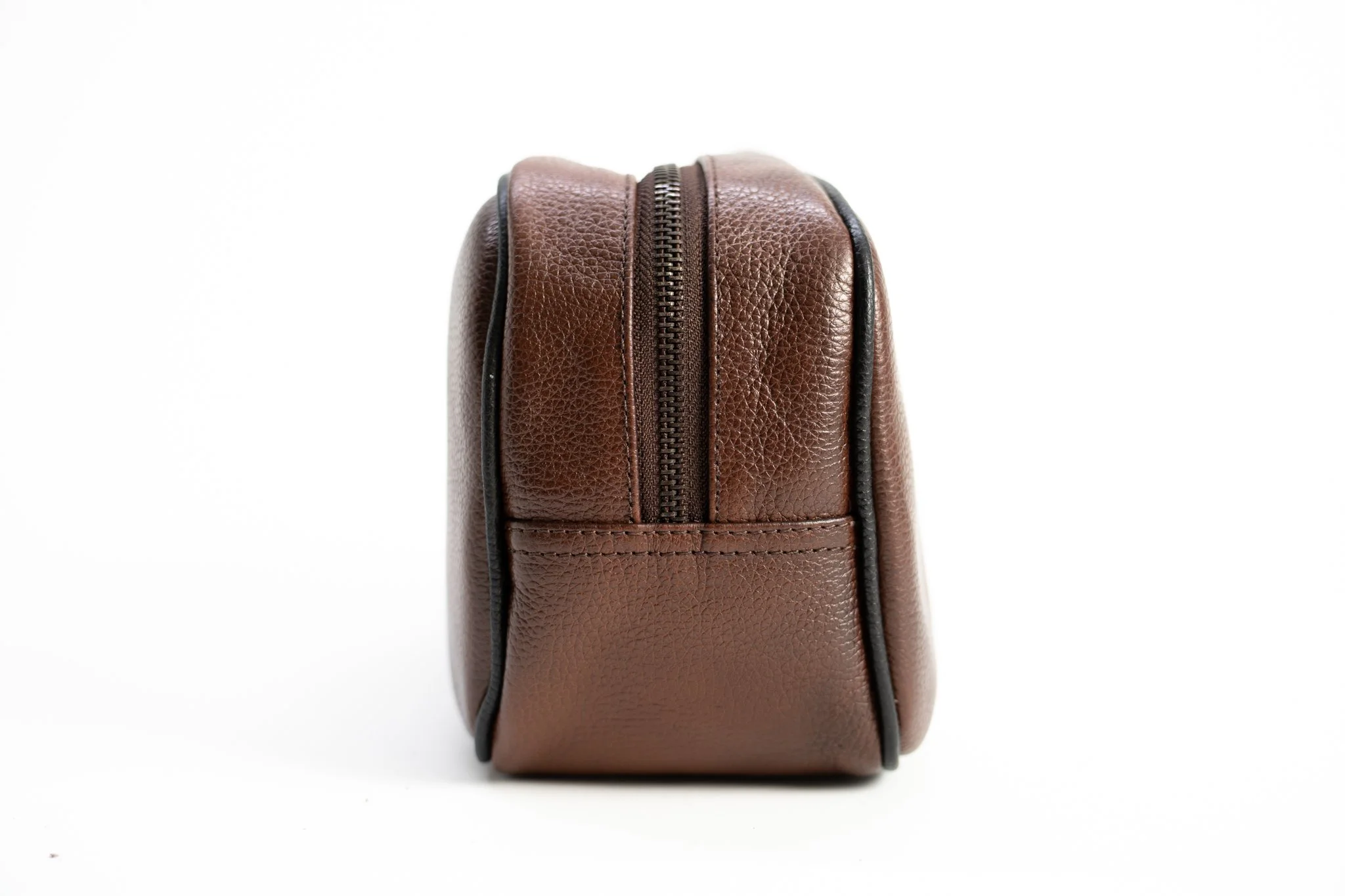 Close-up of a brown textured leather bag with a zippered top against a white background.