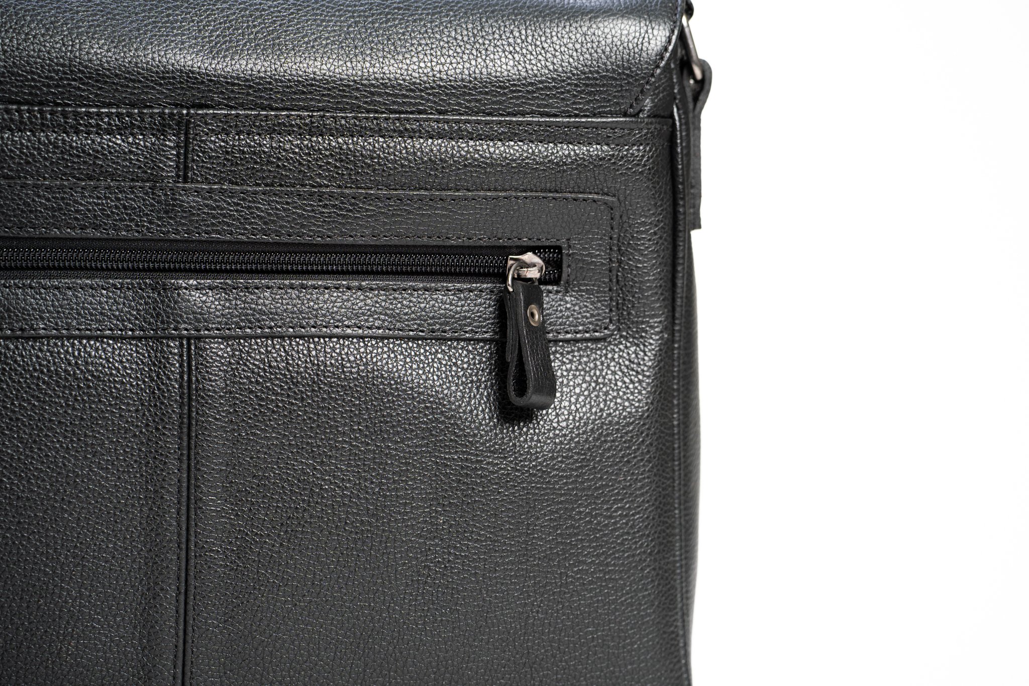 Close-up of a black textured leather bag with a zippered pocket and a zipper pull.