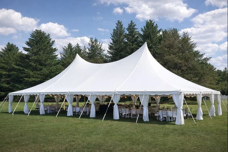 40x60 Peachy Classic Pole Tent set up on a grassy field with bistro lighting, draping, and banquet seating for a large outdoor event in Atlanta, GA