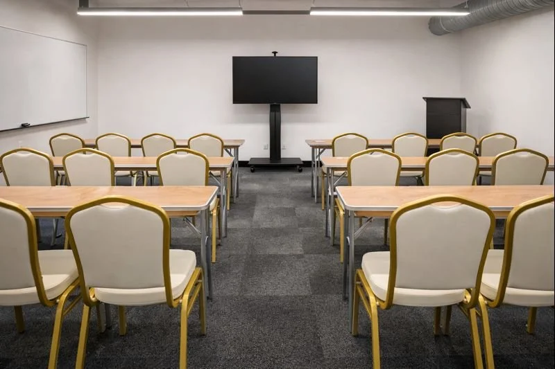 Corporate training room setup with wood training tables and white Summit chairs with gold frames, arranged classroom-style for a professional meeting in Atlanta.