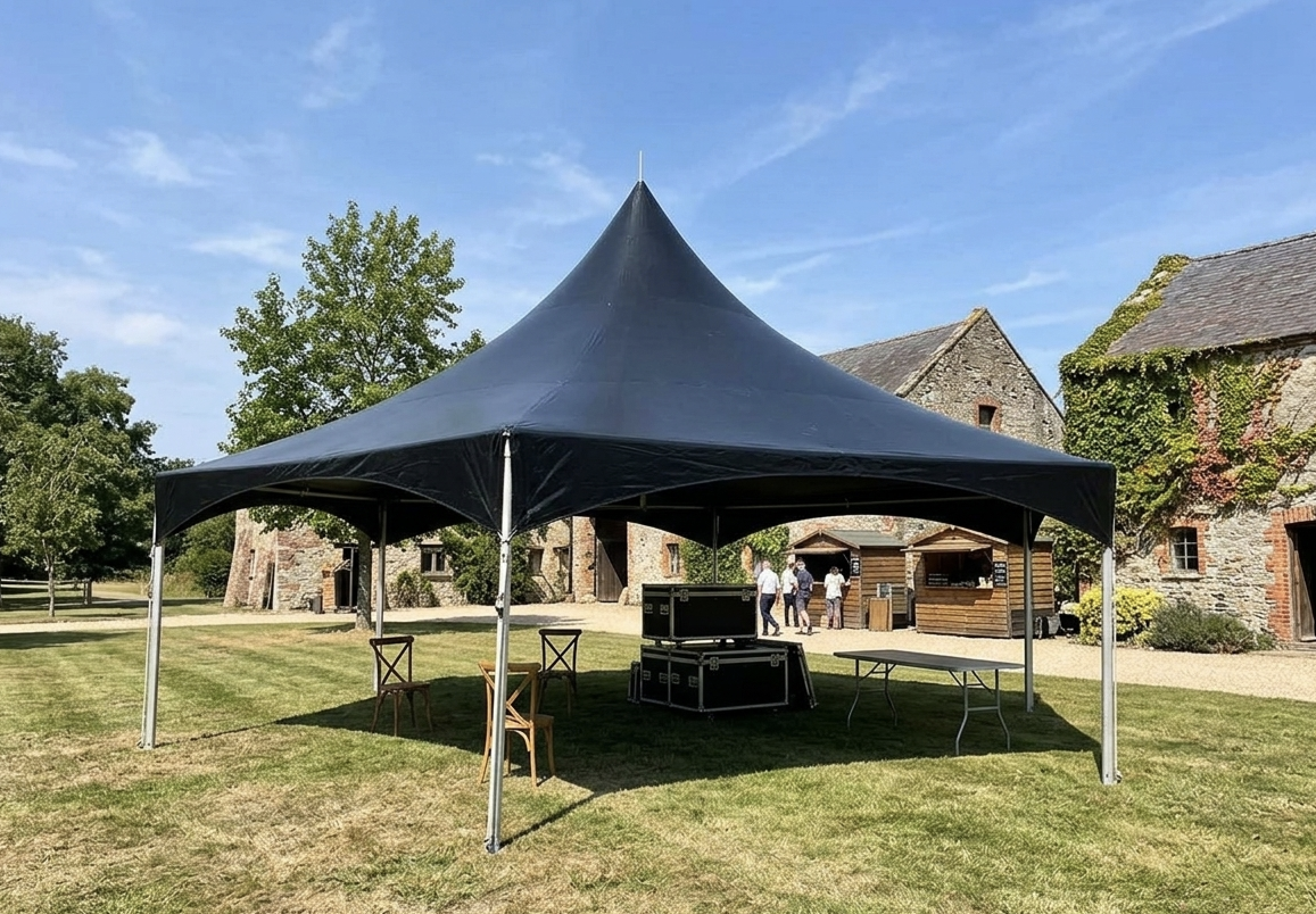 A black 20x20 high peak frame tent installed on grass