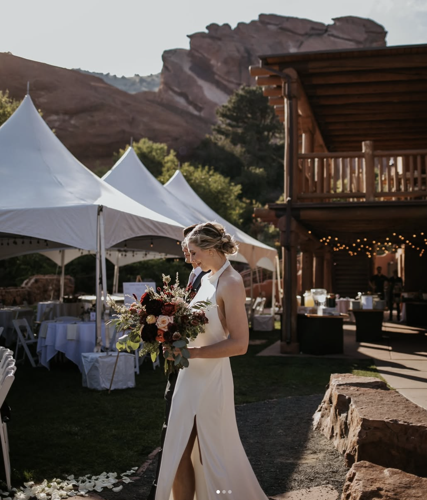 Bride walking through an outdoor wedding venue with white high peak tents set up for a ceremony and reception, highlighting an elegant open-air event layout.