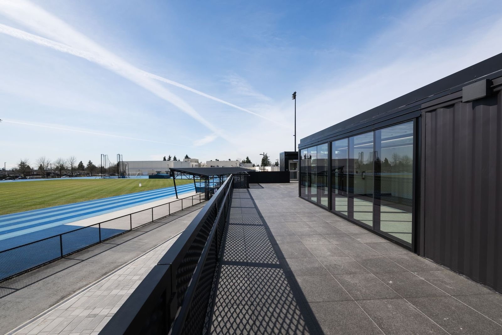 Rooftop terrace of an athletics facility overlooking a blue running track and field