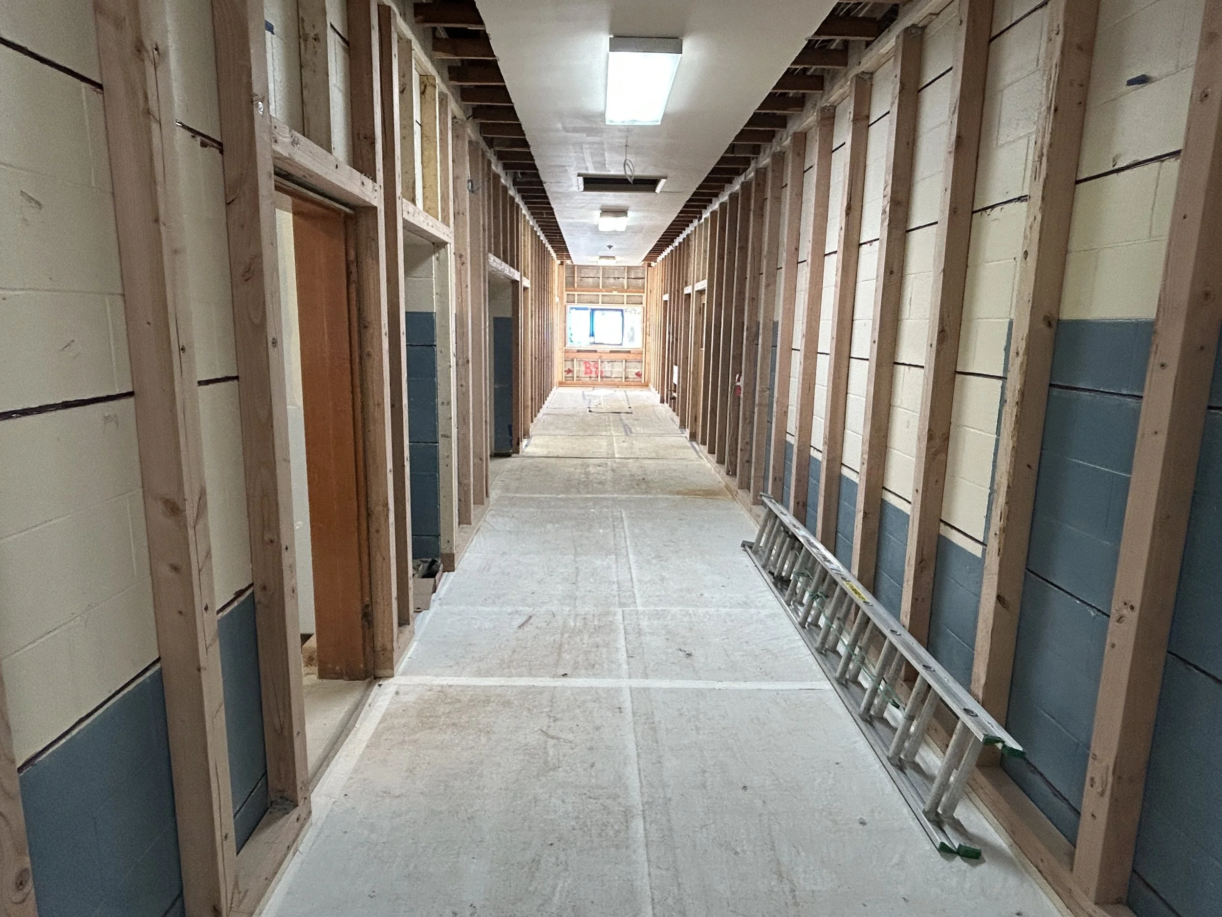 School corridor under construction with wall studs exposed during interior demolition and framing