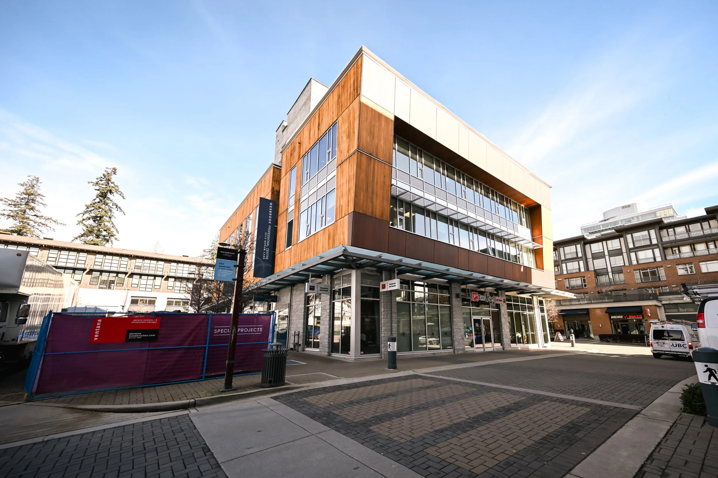 Street-level view of mixed-use office building exterior with construction hoarding for tenant improvement work