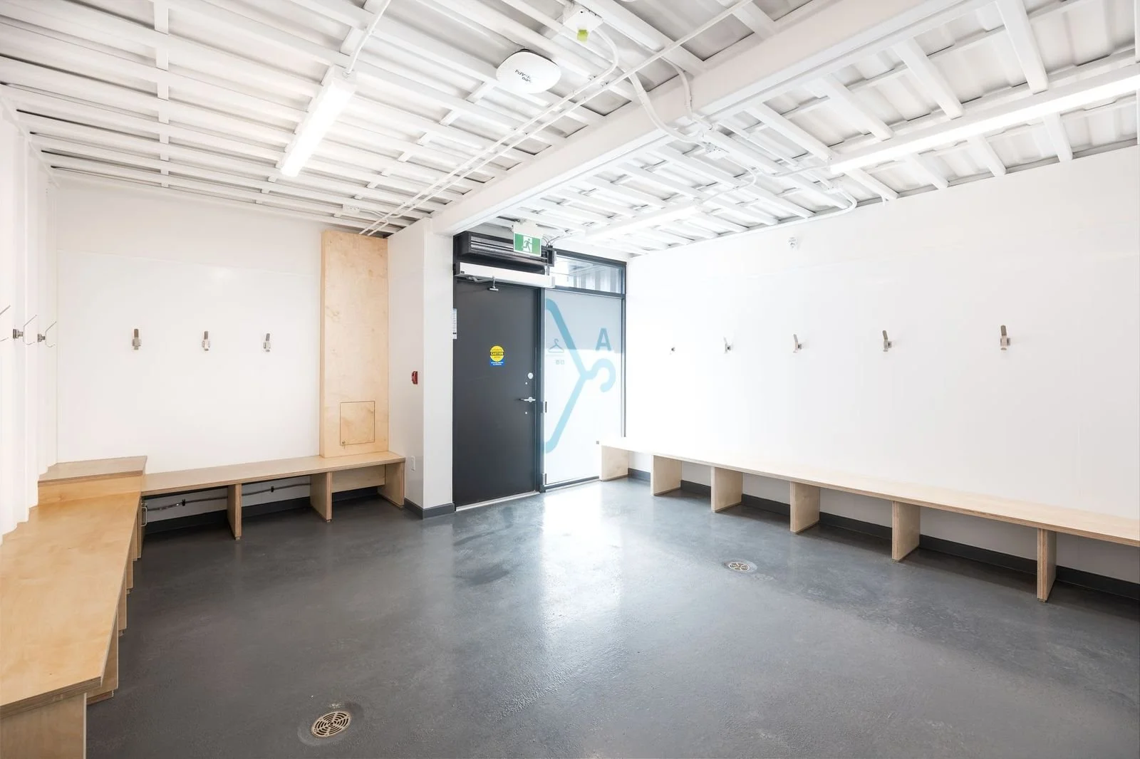 Completed athletic locker room with built-in benches, hooks, and epoxy flooring
