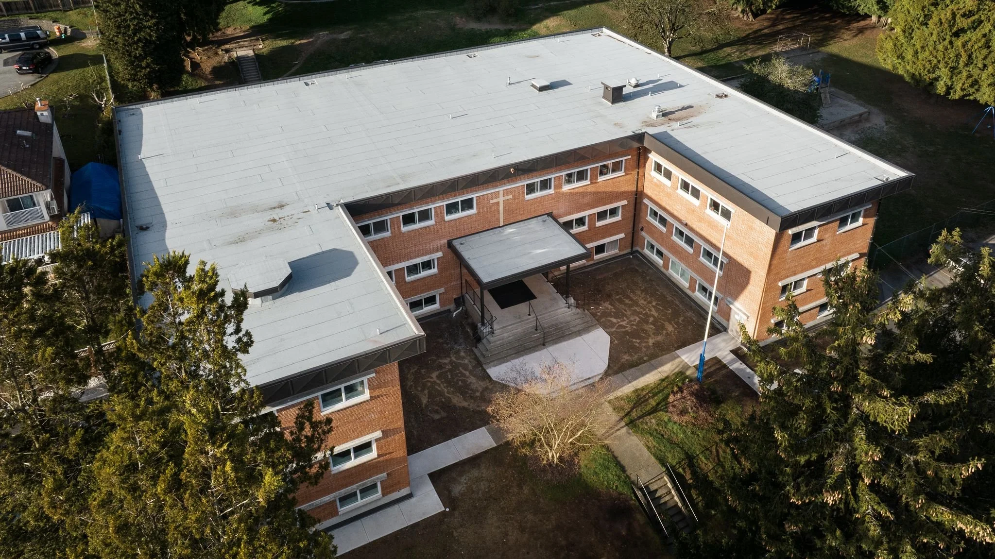 Drone aerial of a completed school campus showing flat roof replacement and courtyard