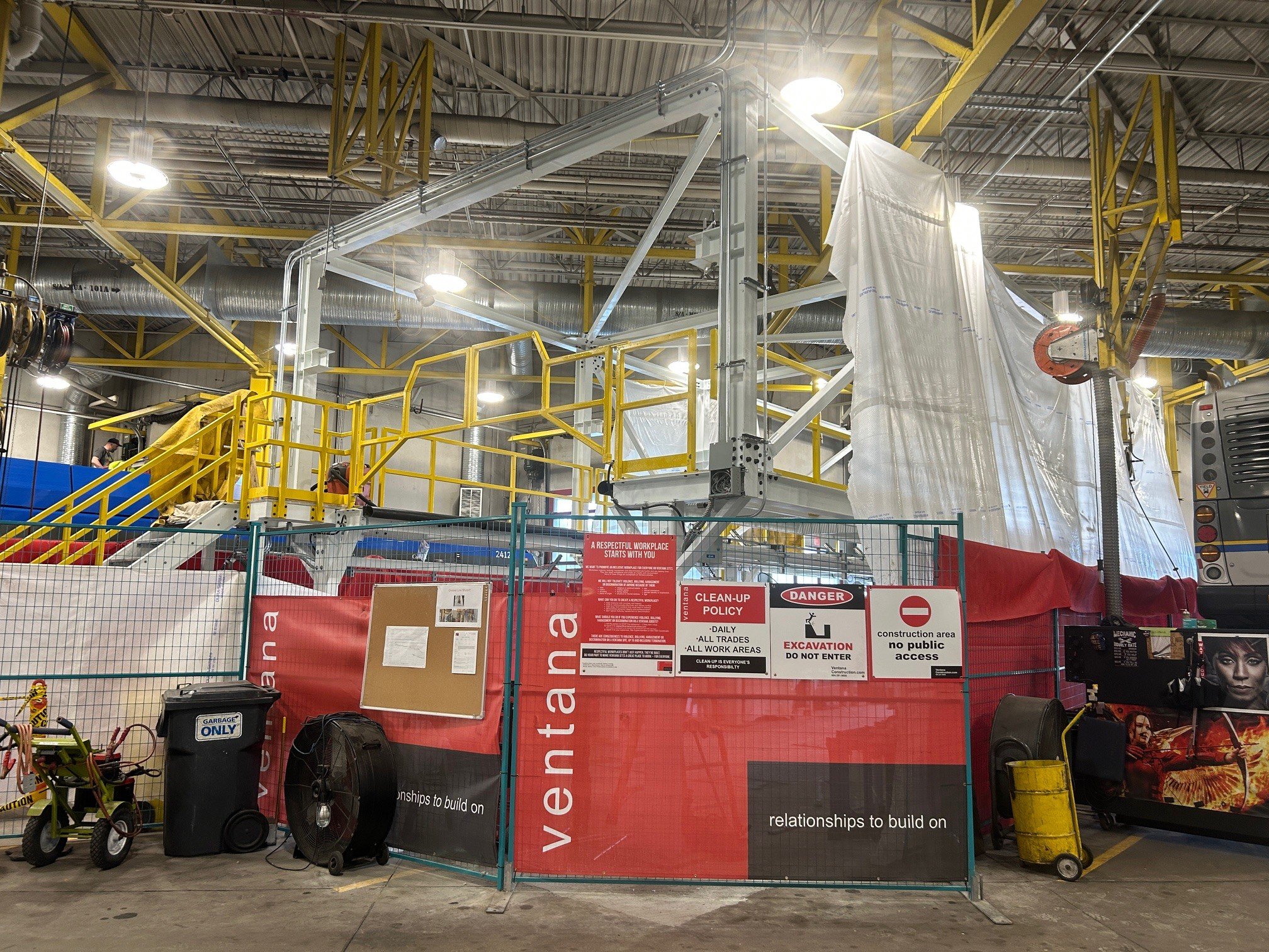 Construction hoarding and yellow access platforms inside an STC bus bay 7 maintenance facility