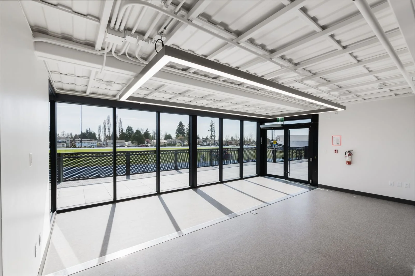 Finished multipurpose room with large glass wall opening to a track-side terrace