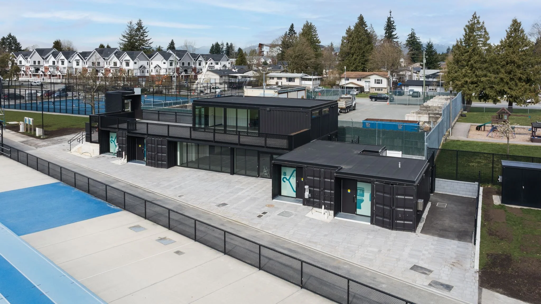 Modular container-based community sports facility beside tennis courts and park