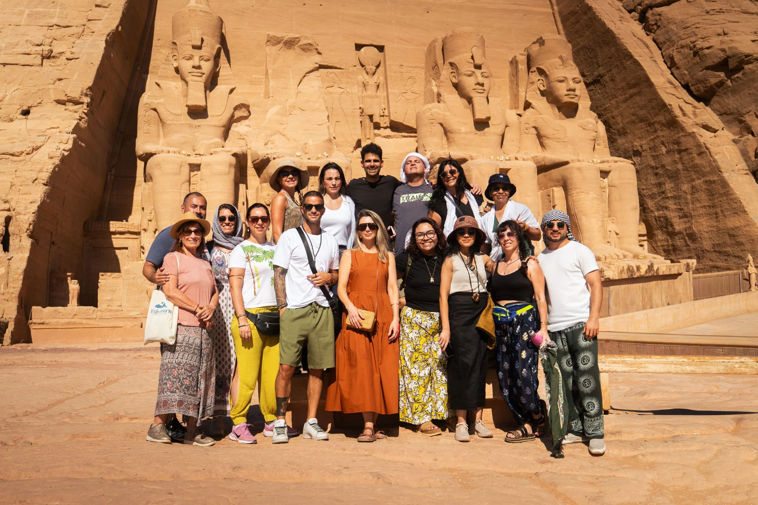 Grupo de personas celebrando en un jardín, todos sonriendo y luciendo ropa casual y colorida, con árboles y vegetación verde de fondo.
