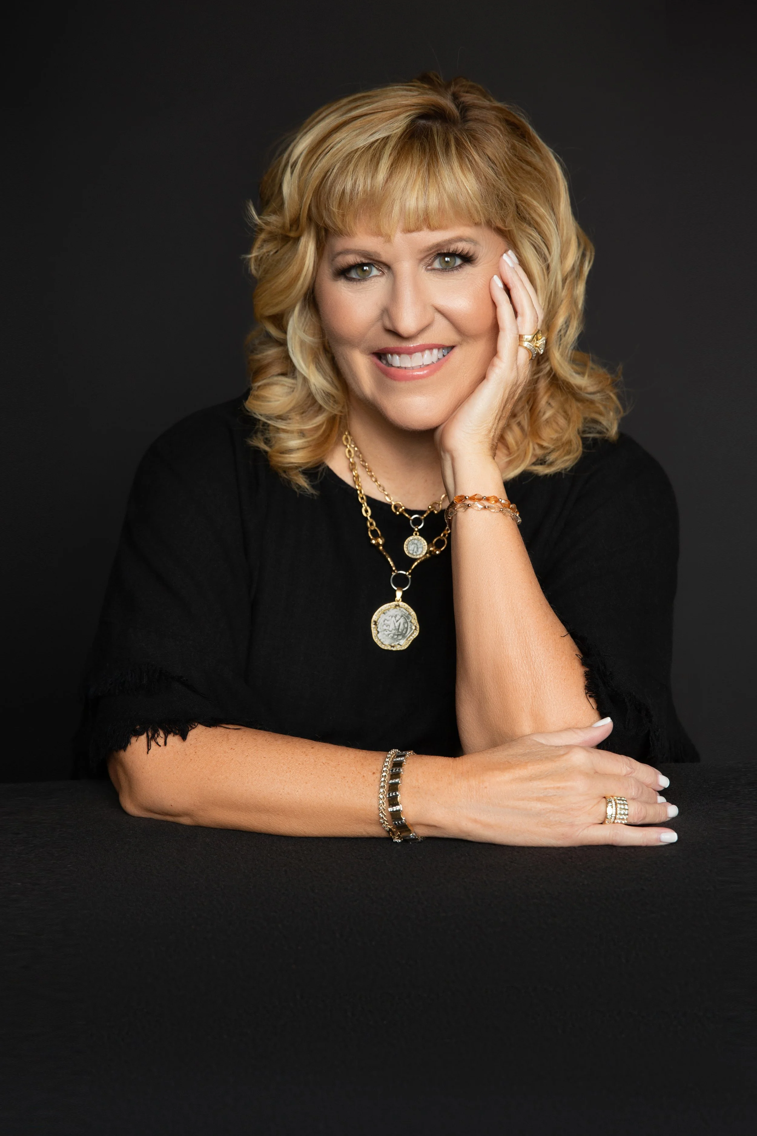 woman smiling white hair blue shirt hand on cheek