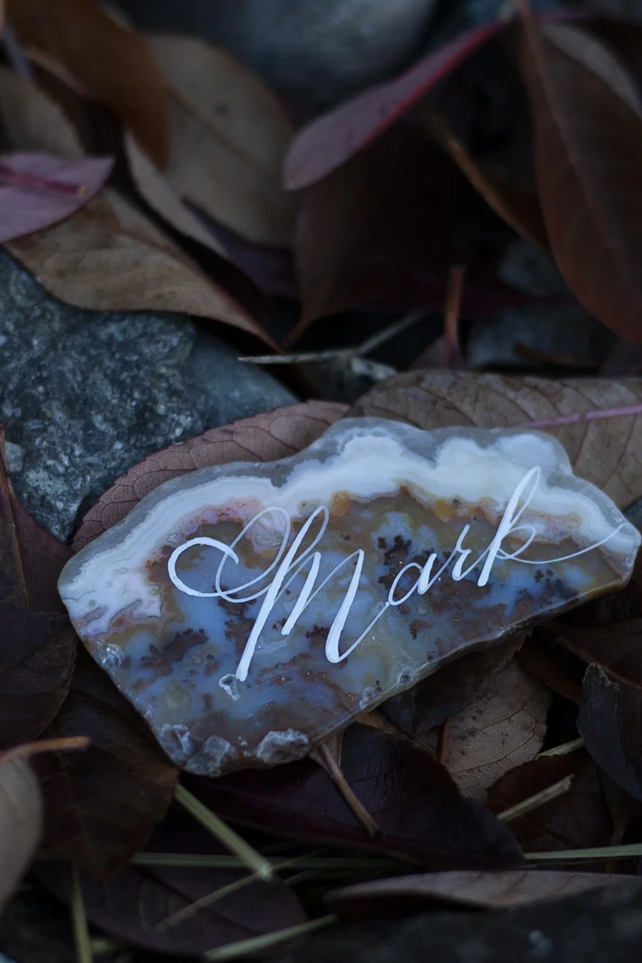 modern calligraphy place cards on unique rock slabs in bright white calligraphy ink