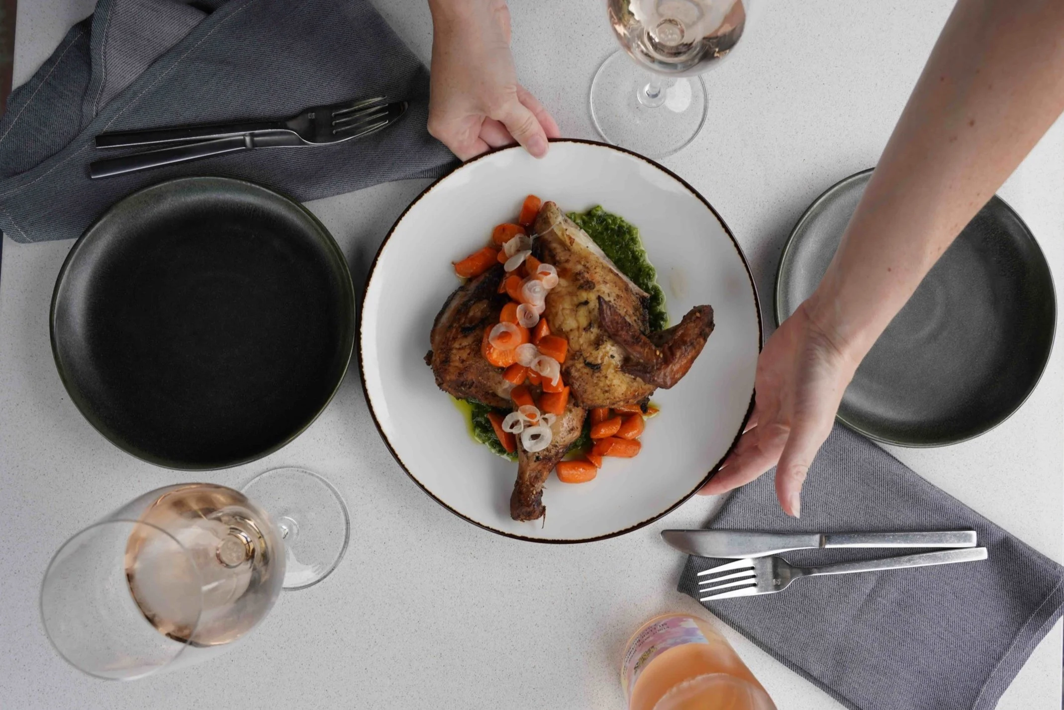 Serving a half chicken with local Vermont greens, carrots, and shallots with two glasses of rose