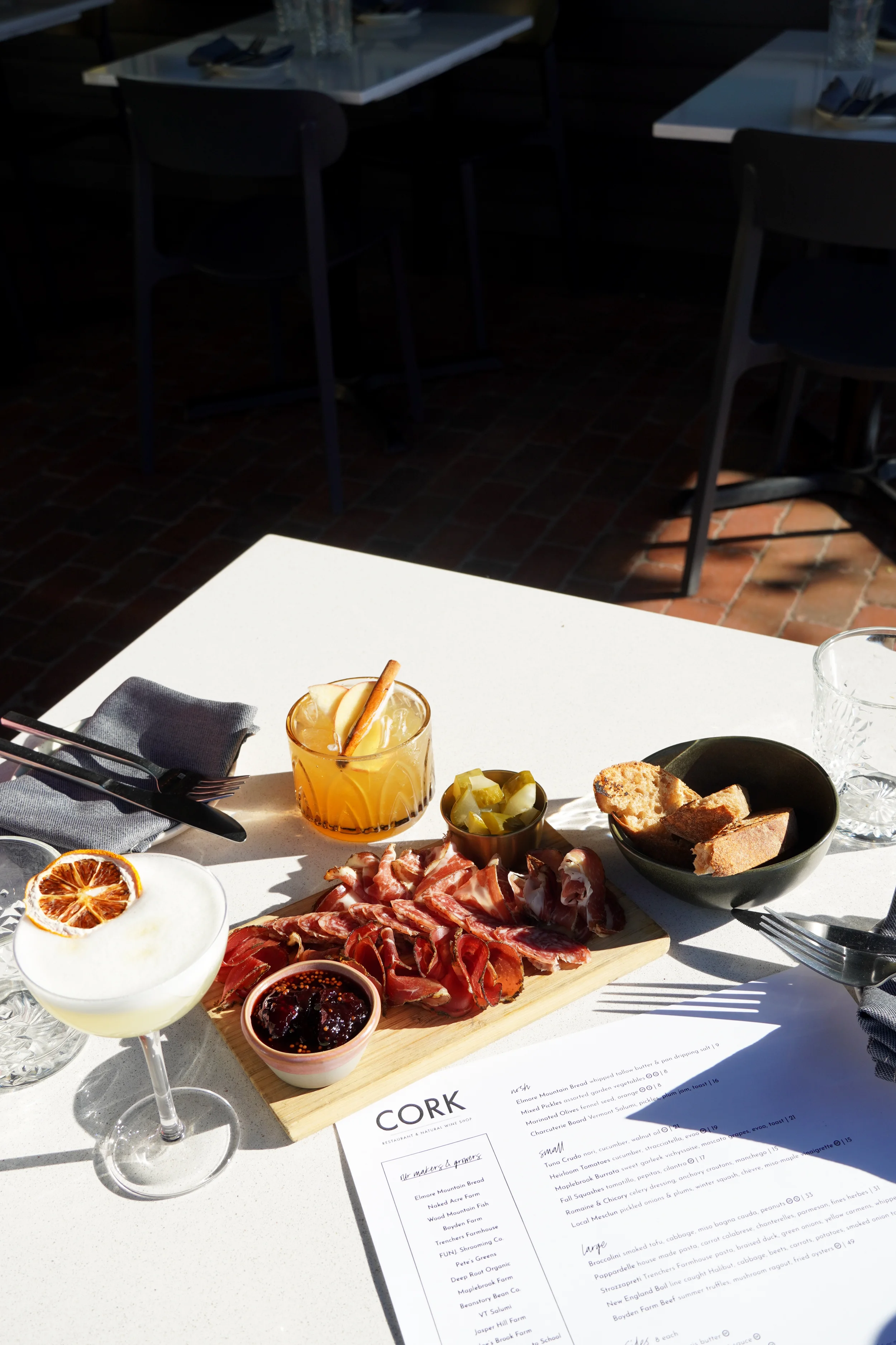 Charcuterie board with locally sourced cured meats, Vermont cheeses, house accompaniments, and cocktails at Cork Restaurant in Stowe, Vermont, highlighting regional flavors and thoughtful hospitality.