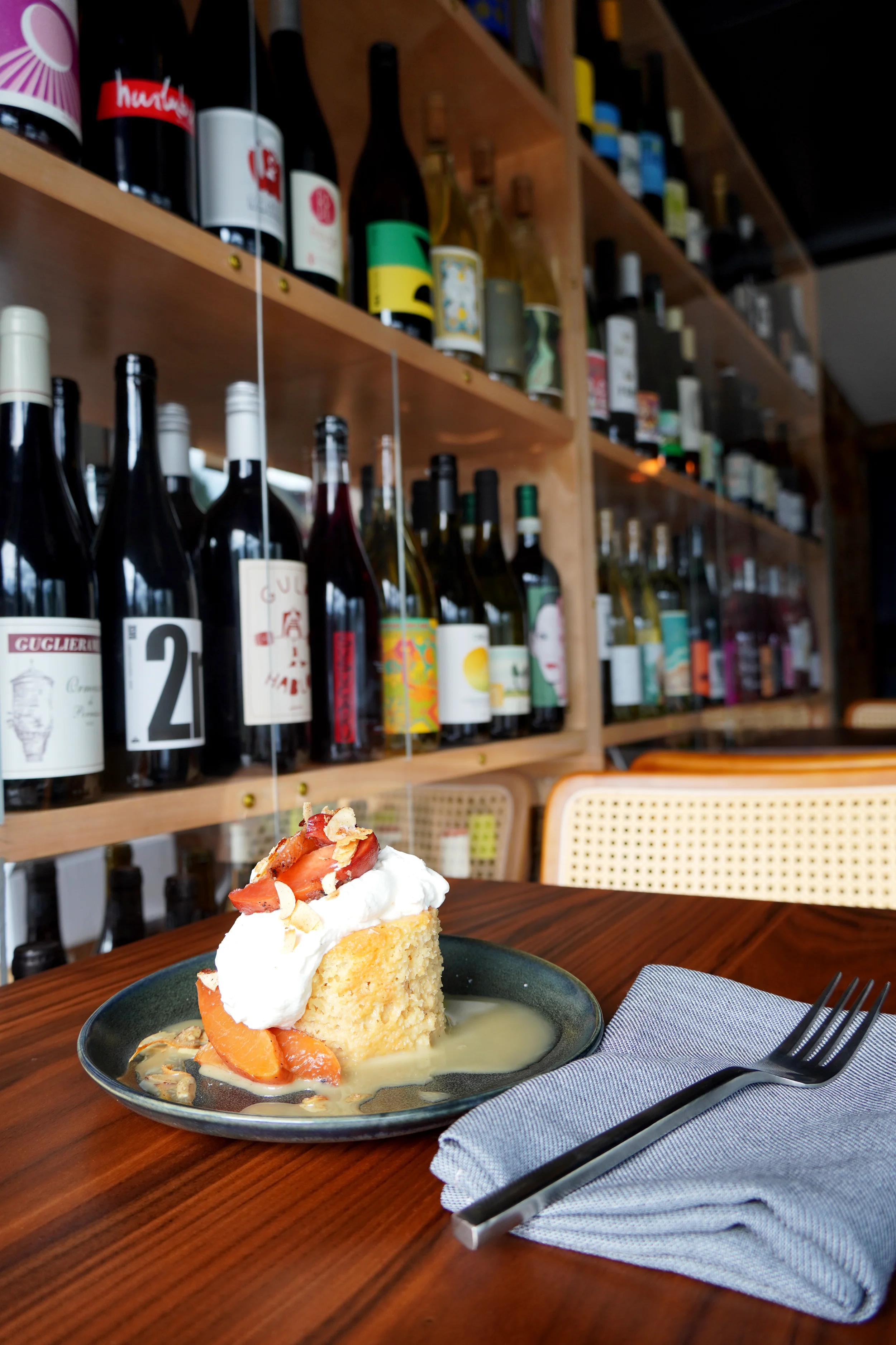 House-made flan cake served with ripe peaches and cream at Cork Restaurant in Stowe, Vermont, reflecting refined desserts and seasonal sweetness.