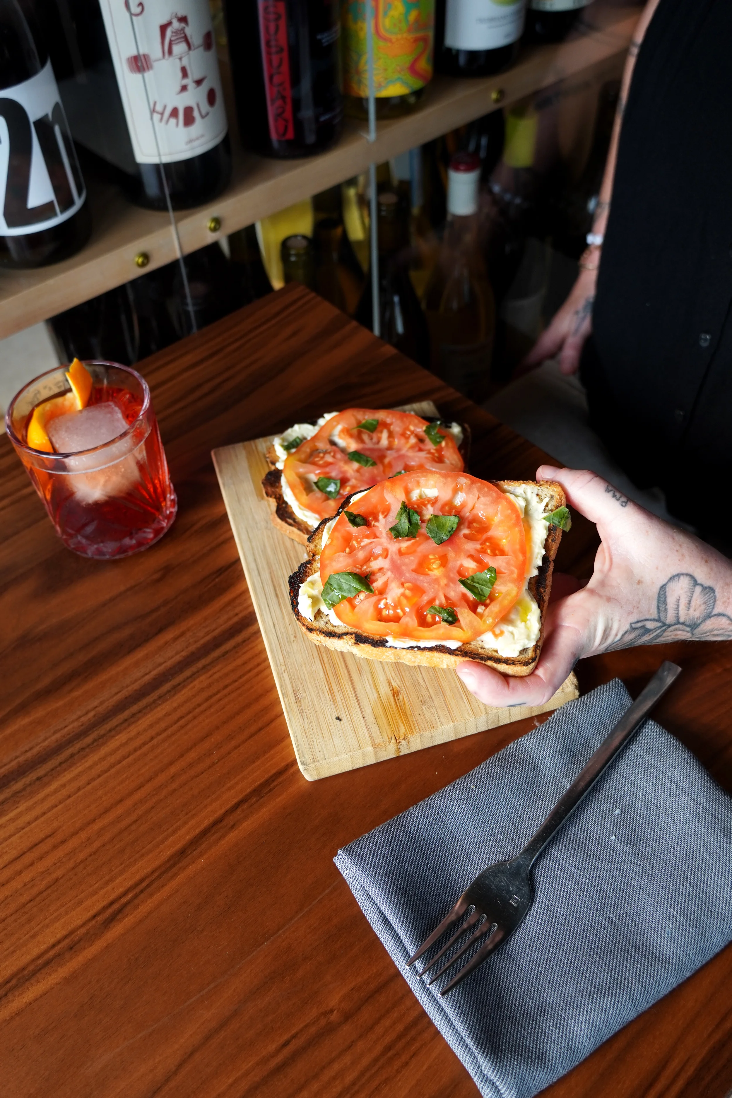 Fresh tomato toast topped with herbs and olive oil alongside a classic Negroni cocktail at Cork Restaurant in Stowe, Vermont, blending simple ingredients and thoughtful bar program.