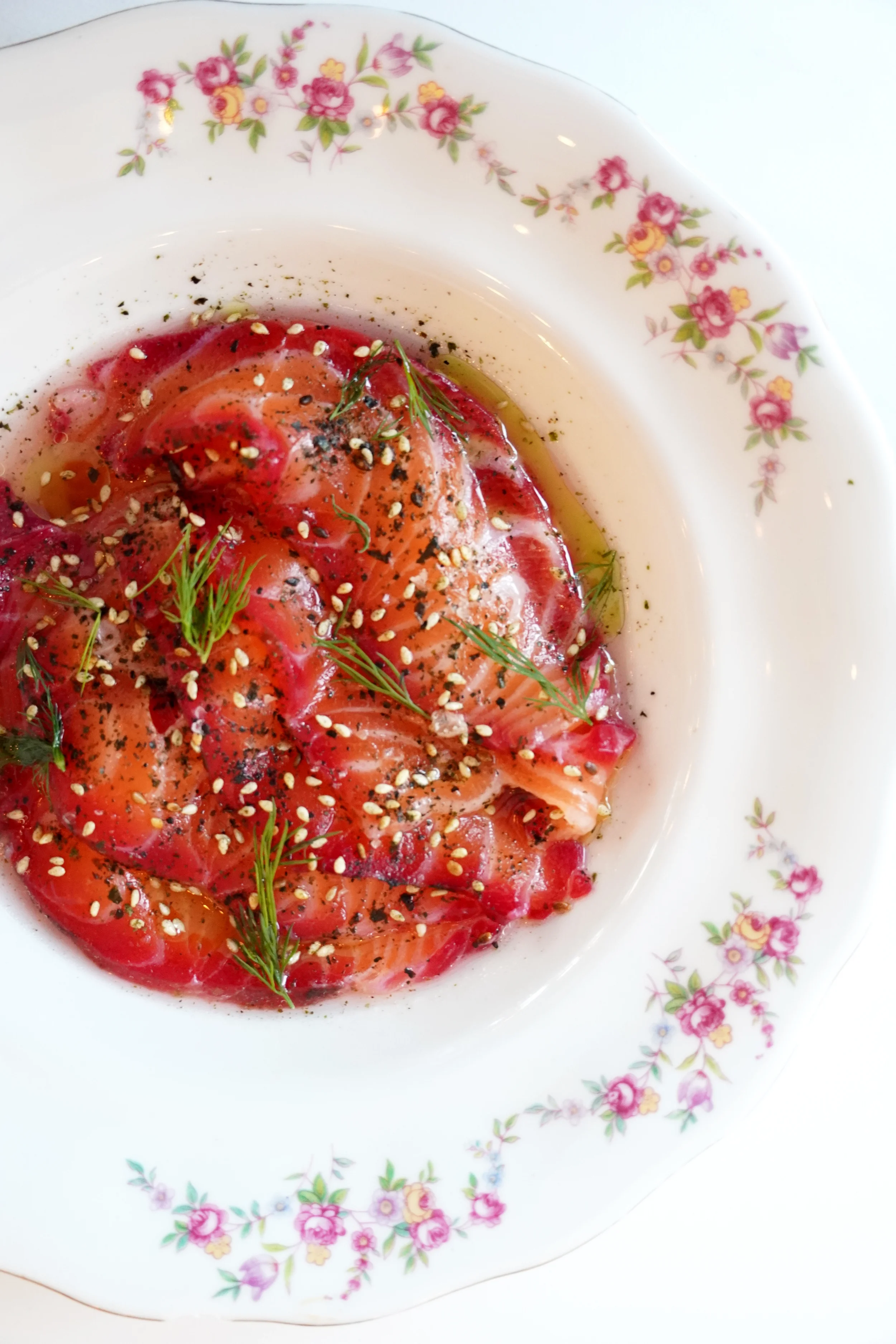 Salmon crudo plated with citrus, olive oil, herbs, and seasoning at Cork Restaurant in Stowe, Vermont, reflecting fresh seafood, thoughtful technique, and modern farm-to-table dining.