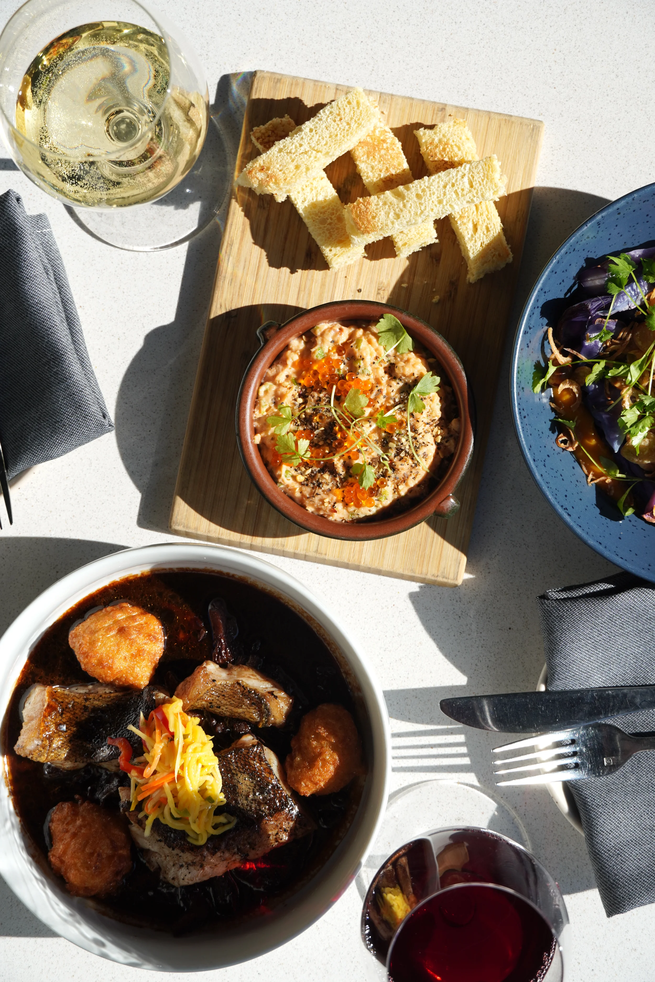 Shared table of seasonal dishes, natural wines, and small plates at Cork Restaurant in Stowe, Vermont, capturing a relaxed and inviting dinner experience.