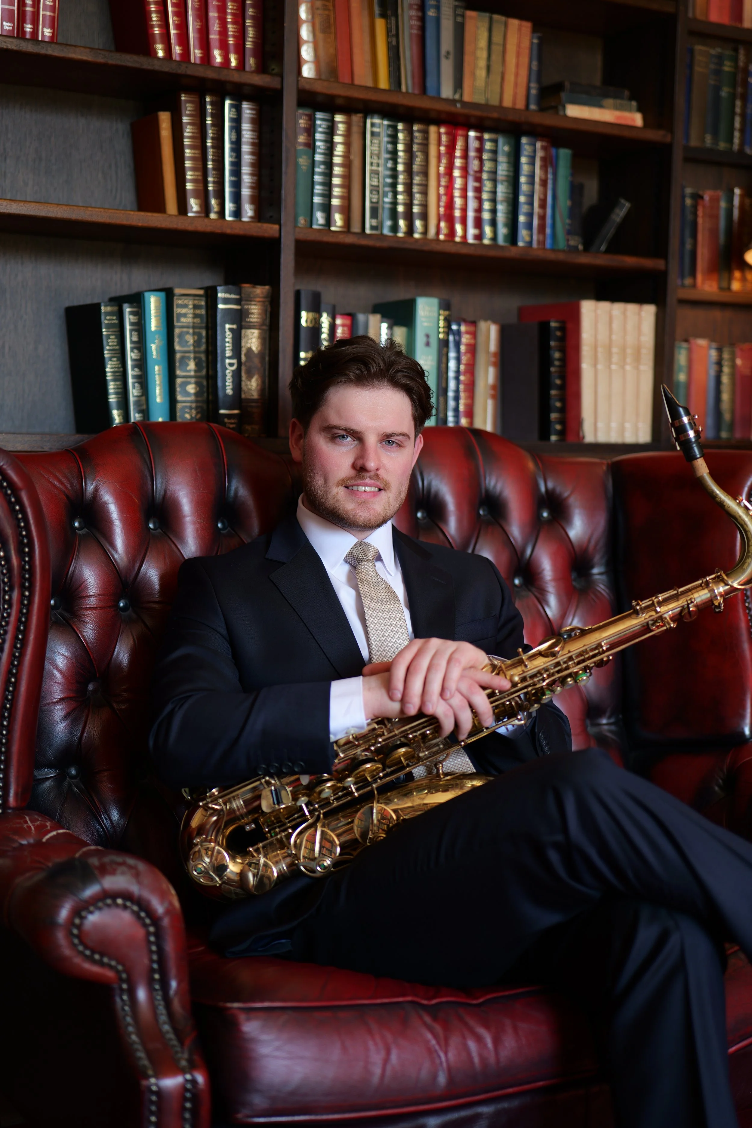 Jazz saxophone player in a suit on a leather couch