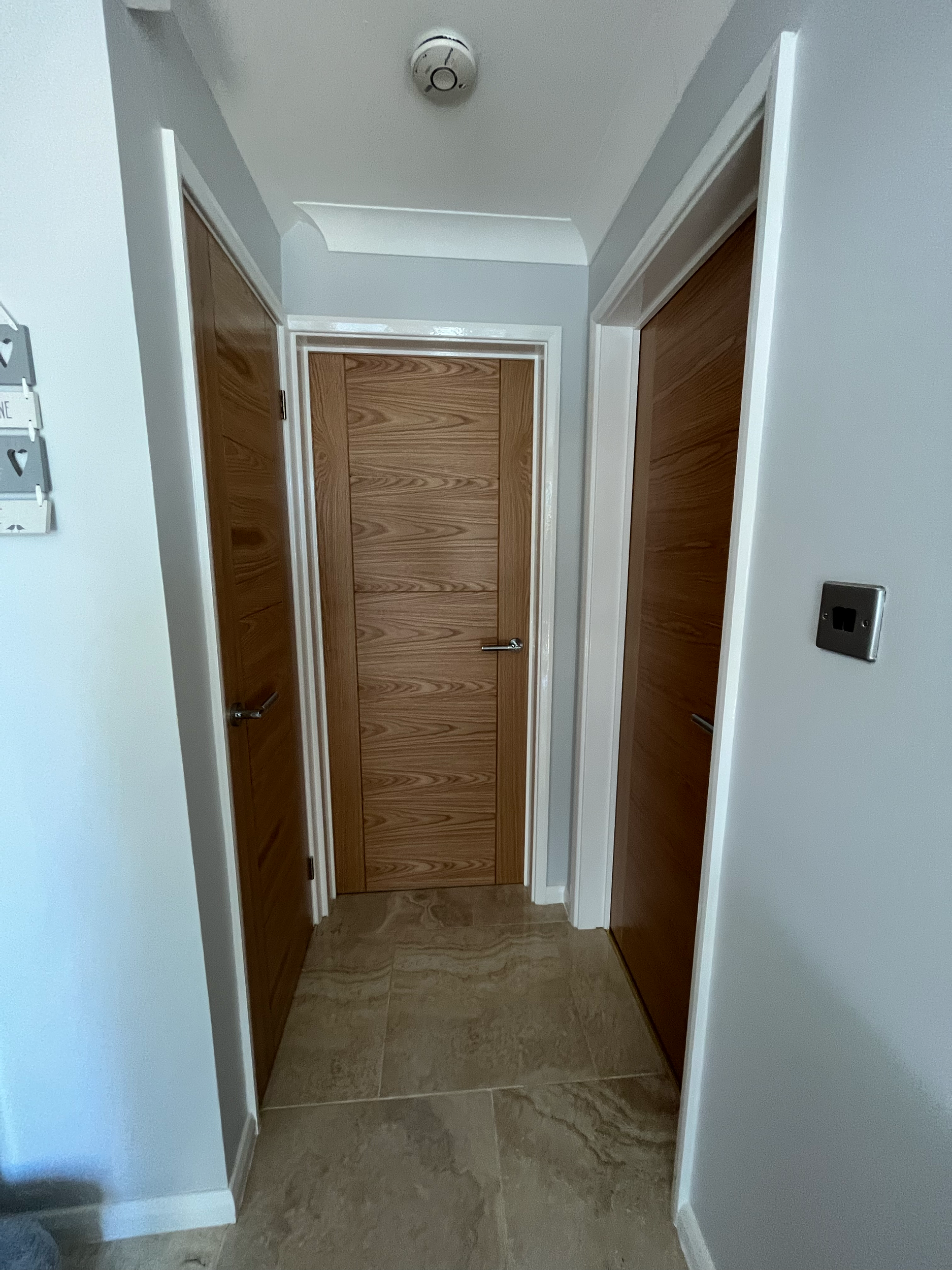 Hallway with multiple wooden doors and tiled floor