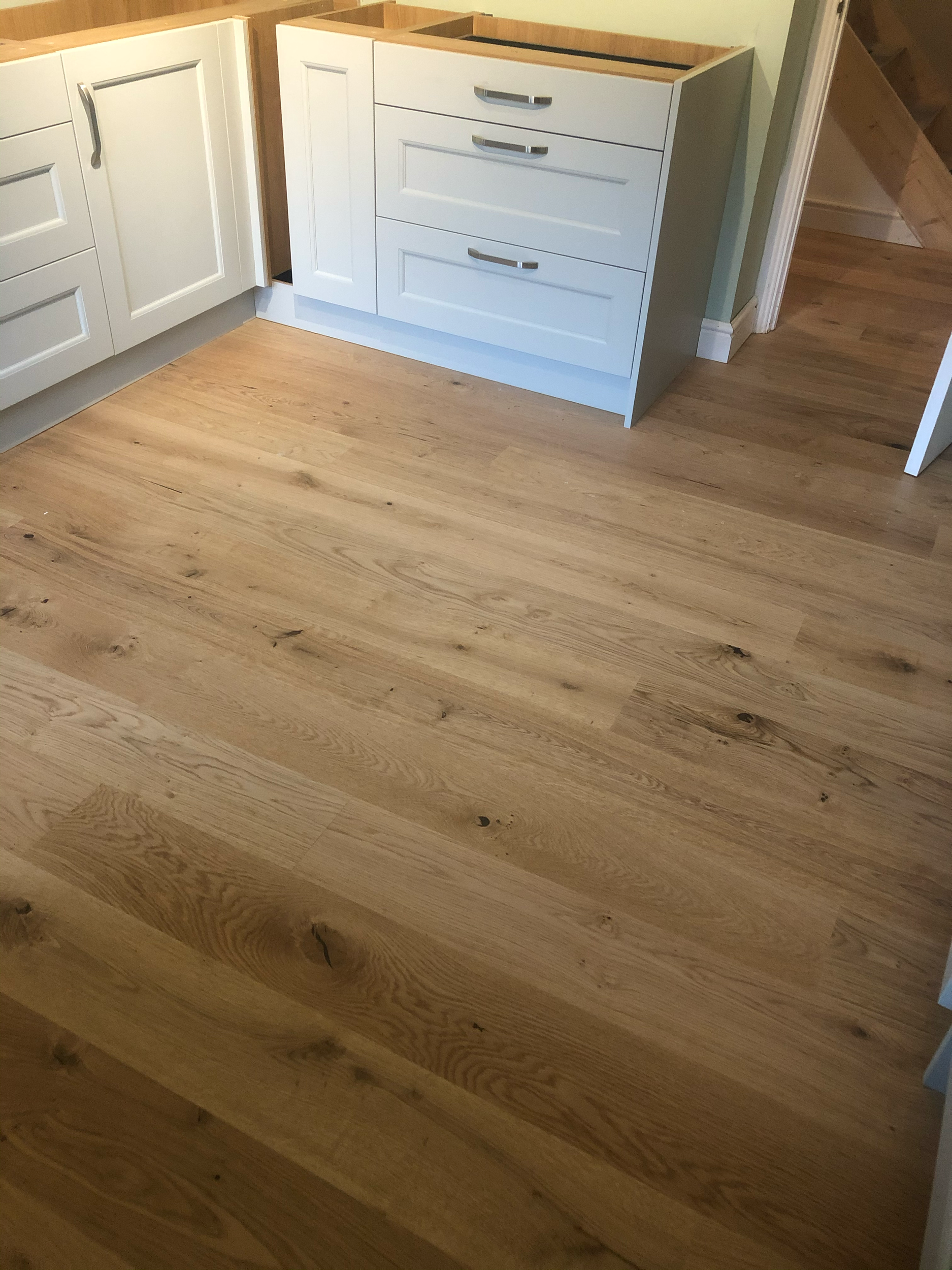 Wooden flooring with white cabinets and drawers positioned in a corner.