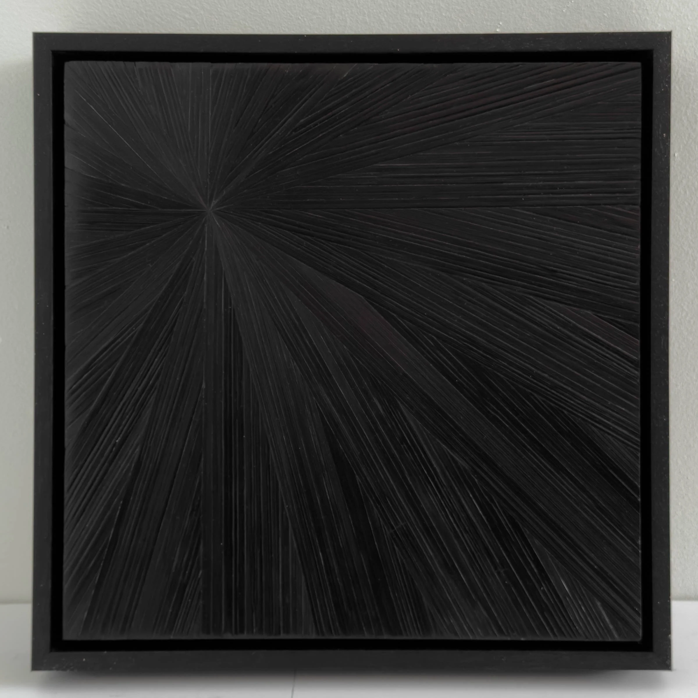 Straw marquetry artwork in a radial pattern creates luminous reflections of light. Black. 12in x 12in. Framed.