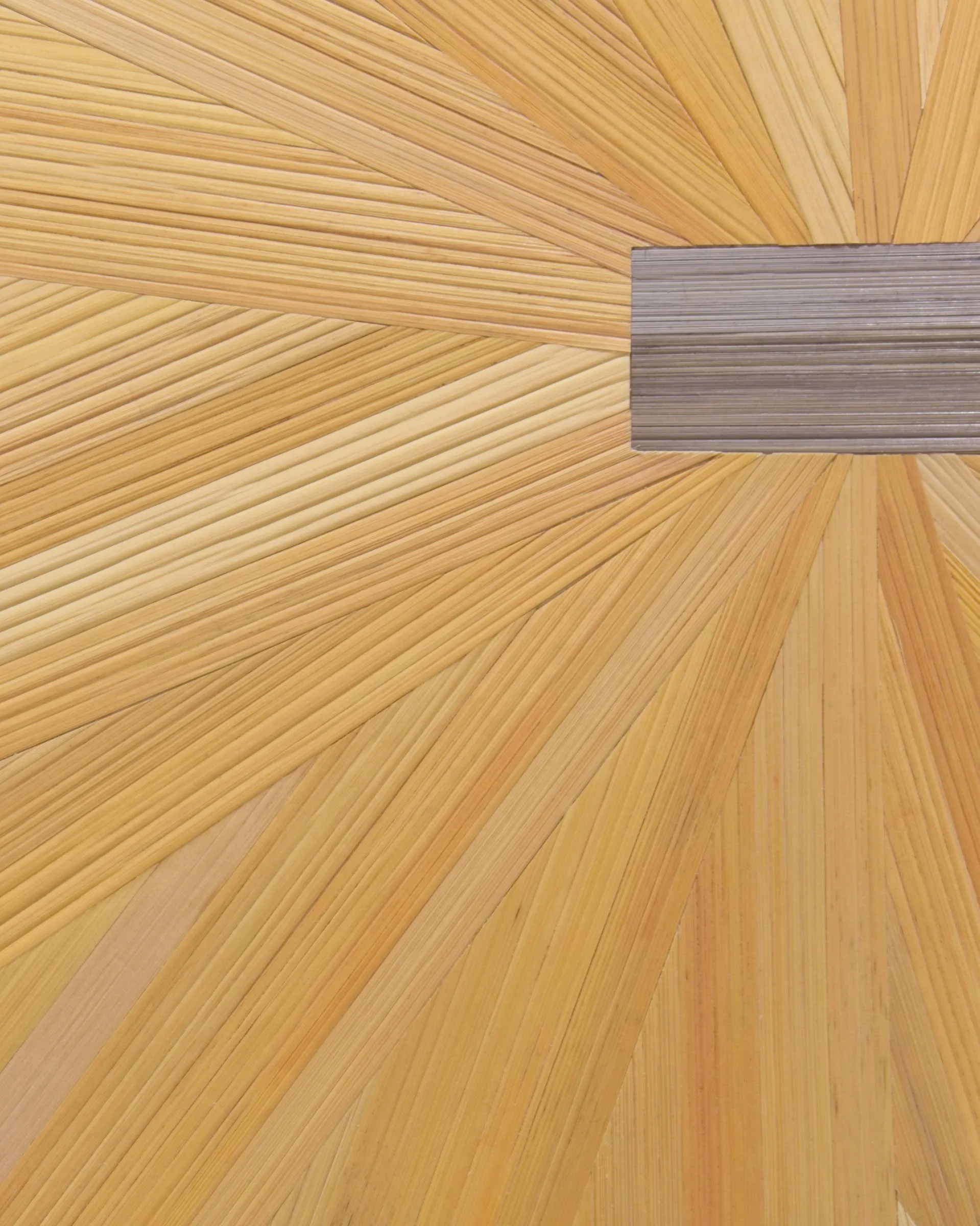 Close detail of hand-dyed rye straw in golden yellow radiating from the center of a straw marquetry floral pinwheel; organic fiber texture and silken sheen visible in the straw surface