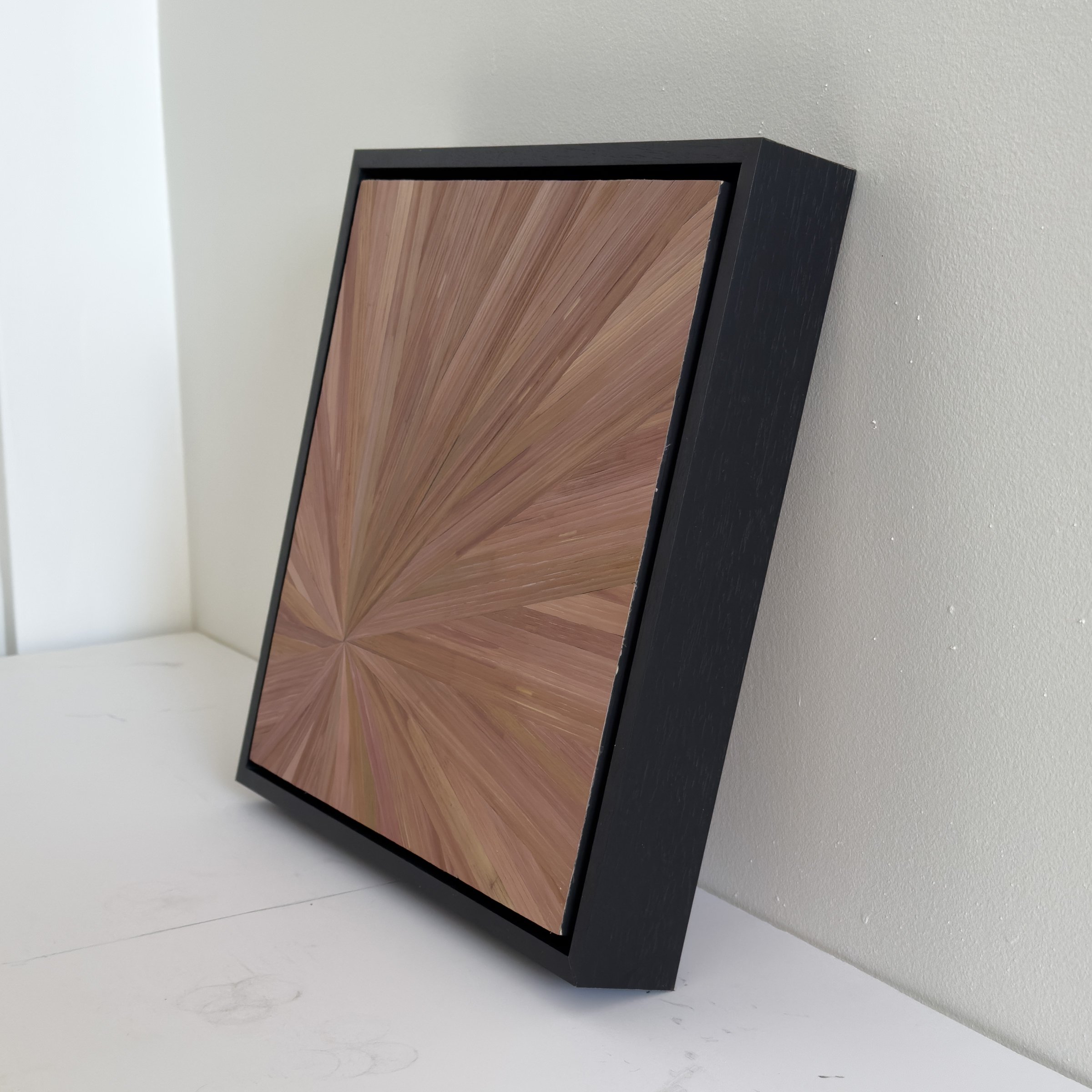 Side view of “Radiance” in Pink, showcasing the reflective nature of the straw marquetry and the way its radial composition shifts dynamically with light.